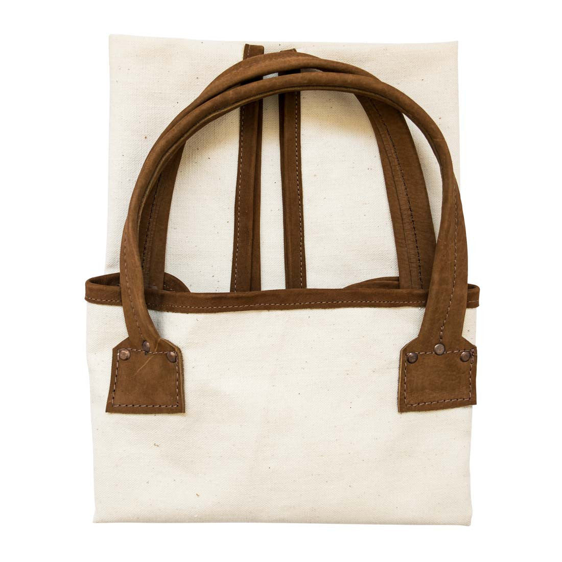 Hide & Drink Firewood Bag showcasing the smooth canvas and leather combination while nestled comfortably on the ground, emphasizing its artisan quality. Firewood Bag With Leather Liner, Full Grain Leather, StockyardX, Small Batch Production, Hand Cut, Hand Sewn, Fire Branded, Artisan, Handmade in La Antigua Guatemala & Oaxaca Mexico.