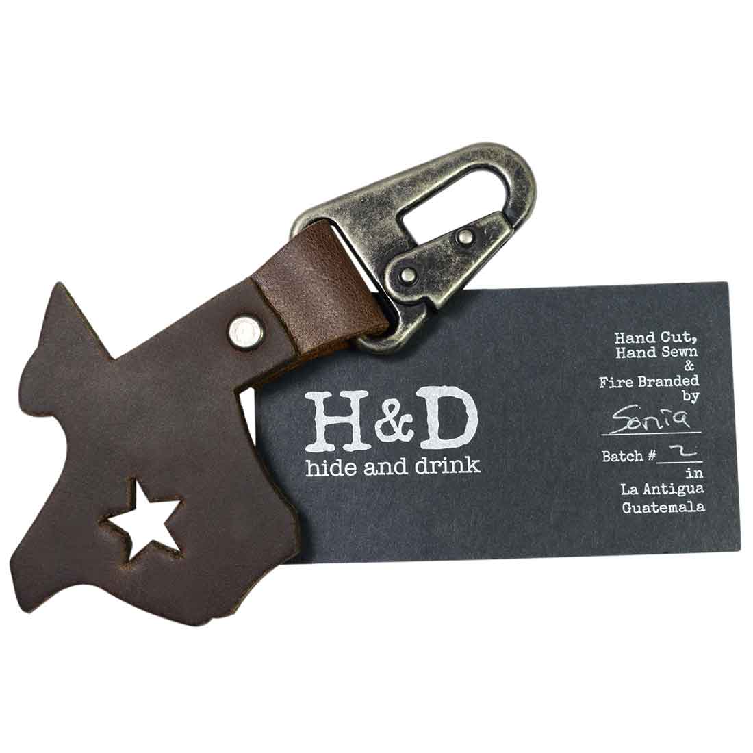 Texas Keychain Holder by Hide & Drink, showcasing a Texas silhouette with a star cutout alongside its branding label. Made of thick full grain leather, this artisan key chain holder reflects small batch production and is a fantastic Texas souvenir.