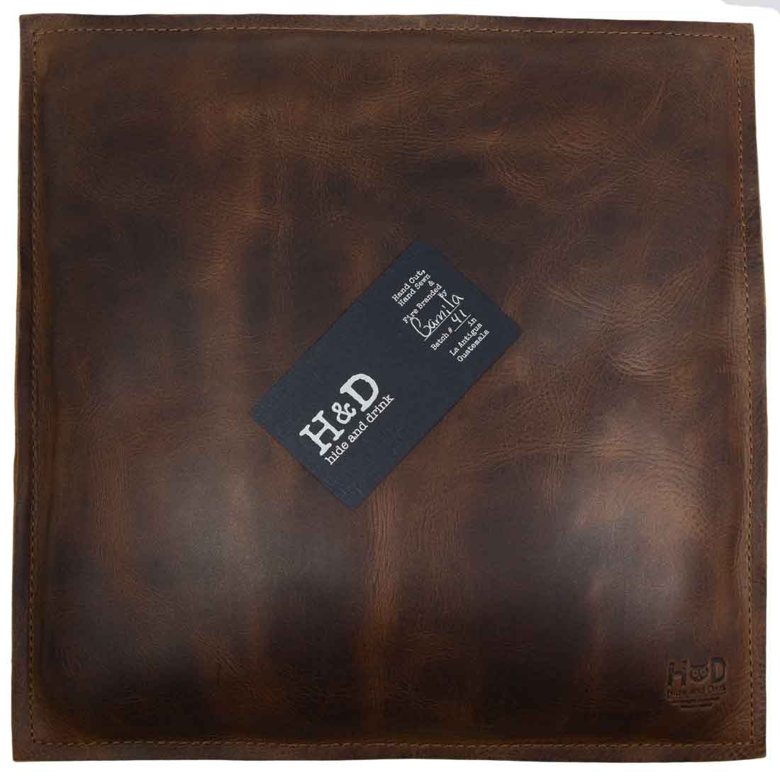 Stylish Hide & Drink Decorative Pillow created with full grain leather, an ideal 12 x 12 in. addition to enhance your couch, sofa, or bed. This charming decoration serves as a unique home and office accessory, embracing small batch production and showcasing hand cut, hand sewn, and fire branded craftsmanship by artisans in La Antigua Guatemala & Oaxaca Mexico.