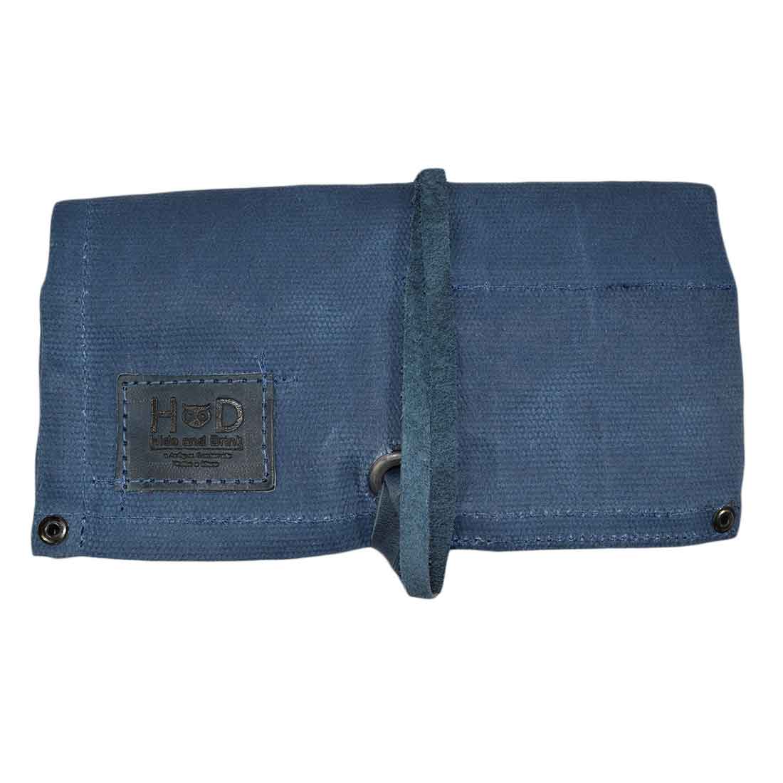 The folded design of Hide & Drink's Waxed Canvas Watch Roll in blue, an artisan piece ideal for organizing watches on-the-go. Perfect for travel and watch storage.