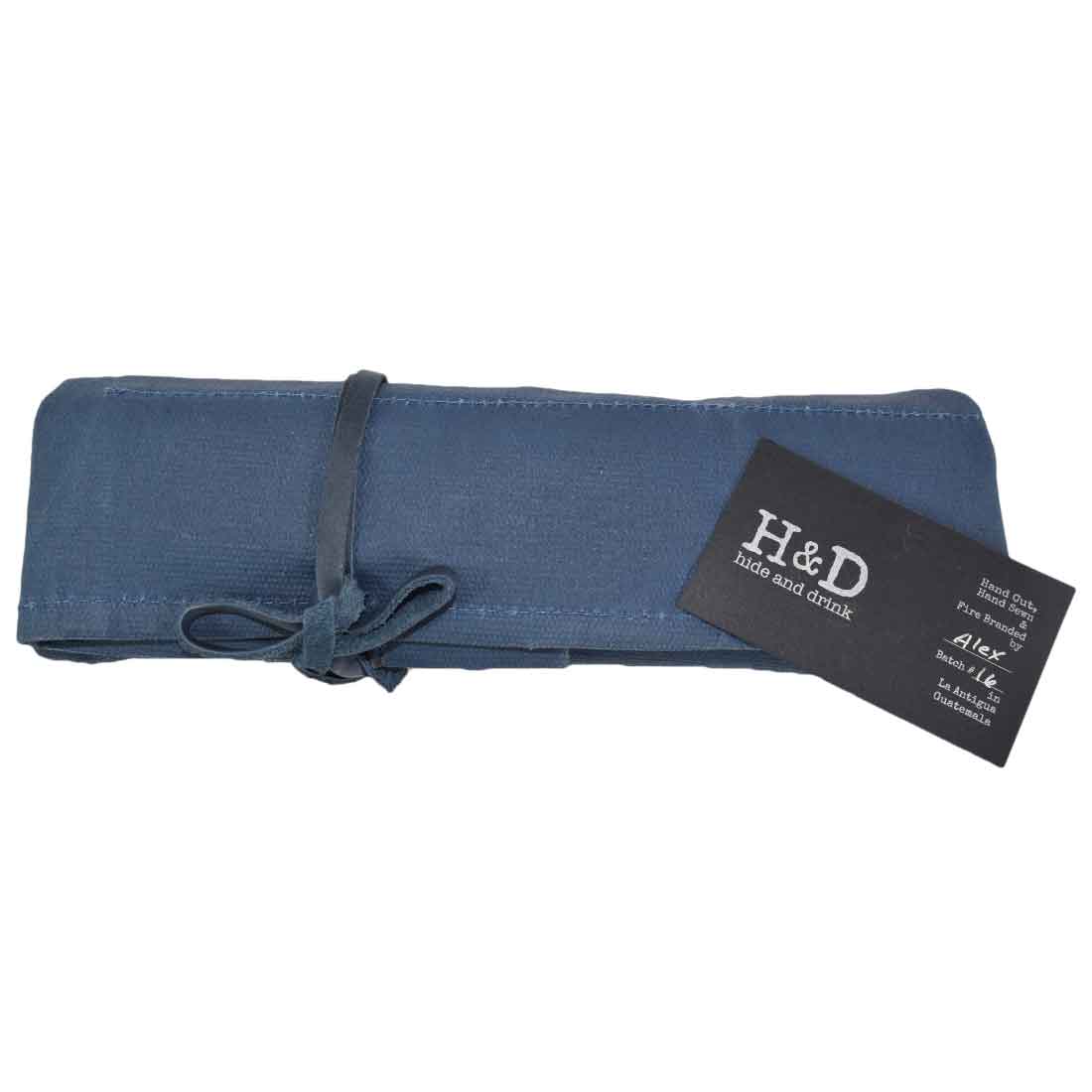 Hide & Drink's Wrench Roll (11 Pockets) rolled up in blue with a cinch. This compact Wrench Tool Roll is ideal for craftsmen needing reliable hanging storage. Made from rugged waxed canvas, it embodies a rustic organizer featuring small batch production, hand cut and hand sewn artistry, and fire branding, handmade in La Antigua Guatemala & Oaxaca Mexico.