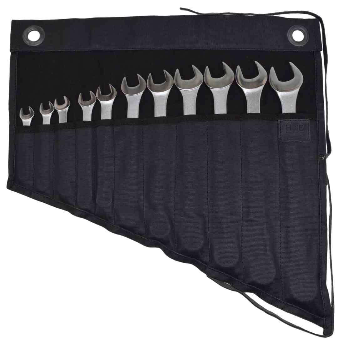 Hide & Drink's Wrench Roll (11 Pockets) displaying a collection of wrenches in a stylish black finish. This Wrench Tool Roll offers efficient hanging storage solutions for craftsmen. Crafted from durable waxed canvas, it serves as a rustic organizer, showcasing small batch production, hand cut and hand sewn features, and fire branding, artisan crafted in La Antigua Guatemala & Oaxaca Mexico.
