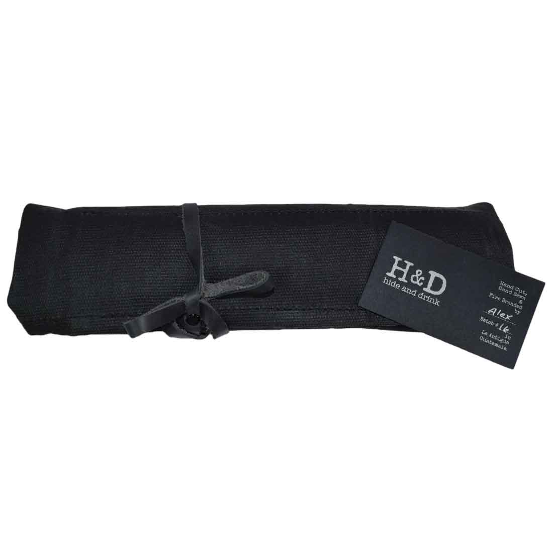 Hide & Drink's Wrench Roll (11 Pockets) rolled and secured with a leather strap, showcasing its convenient portability. This Wrench Tool Roll is perfect for craftsmen who need reliable hanging storage for tools. Made from high-quality waxed canvas, it serves as a rustic organizer featuring small batch production, hand cut and hand sewn artistry, and fire branding, crafted in La Antigua Guatemala & Oaxaca Mexico.