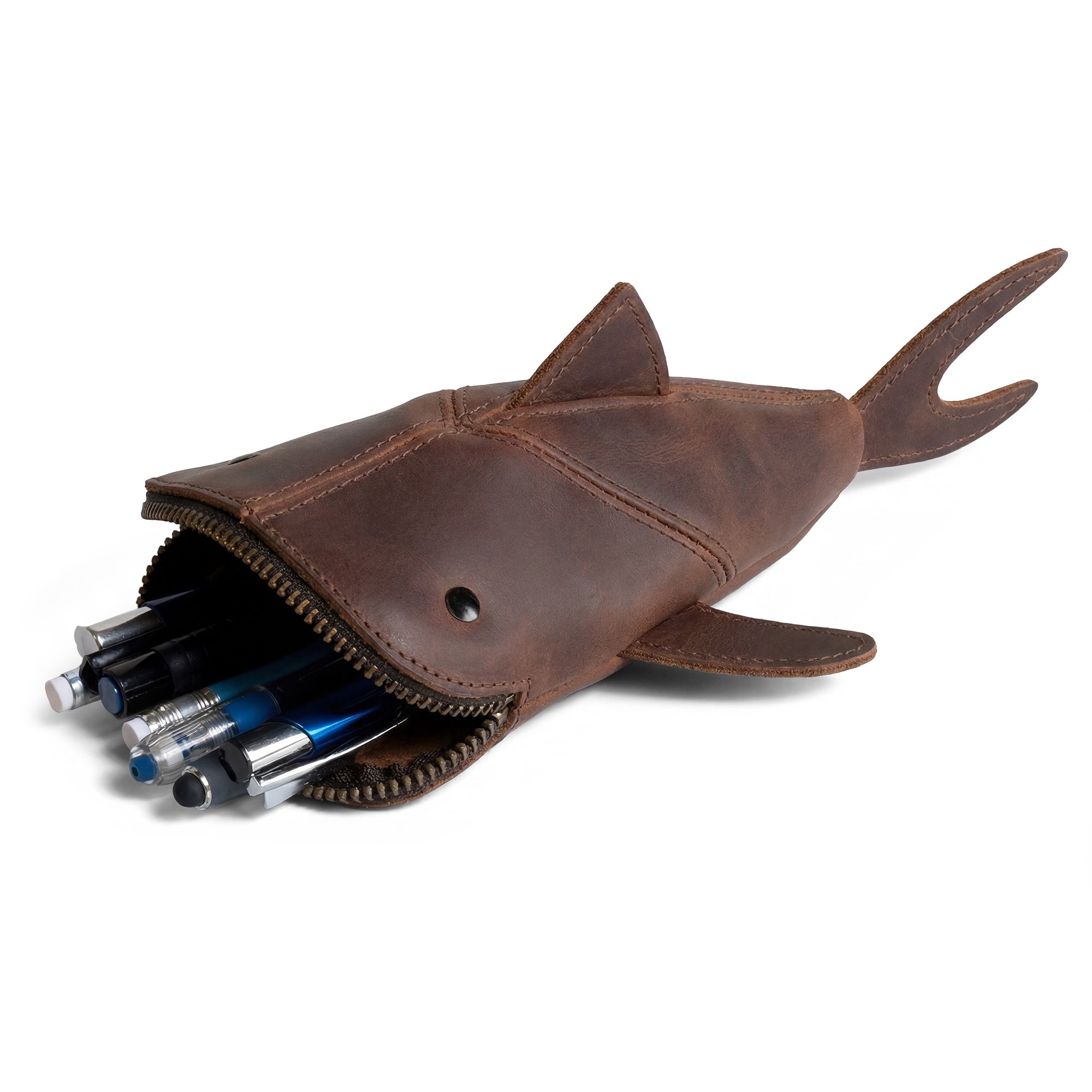 The Leather Shark Pouch by Hide & Drink features a zipper opening with various colorful pens inside, showcasing its versatility as a zippered coin pouch, change bag, and pencil purse, crafted from full grain leather for durability in small batch production, handmade in La Antigua Guatemala & Oaxaca Mexico.
