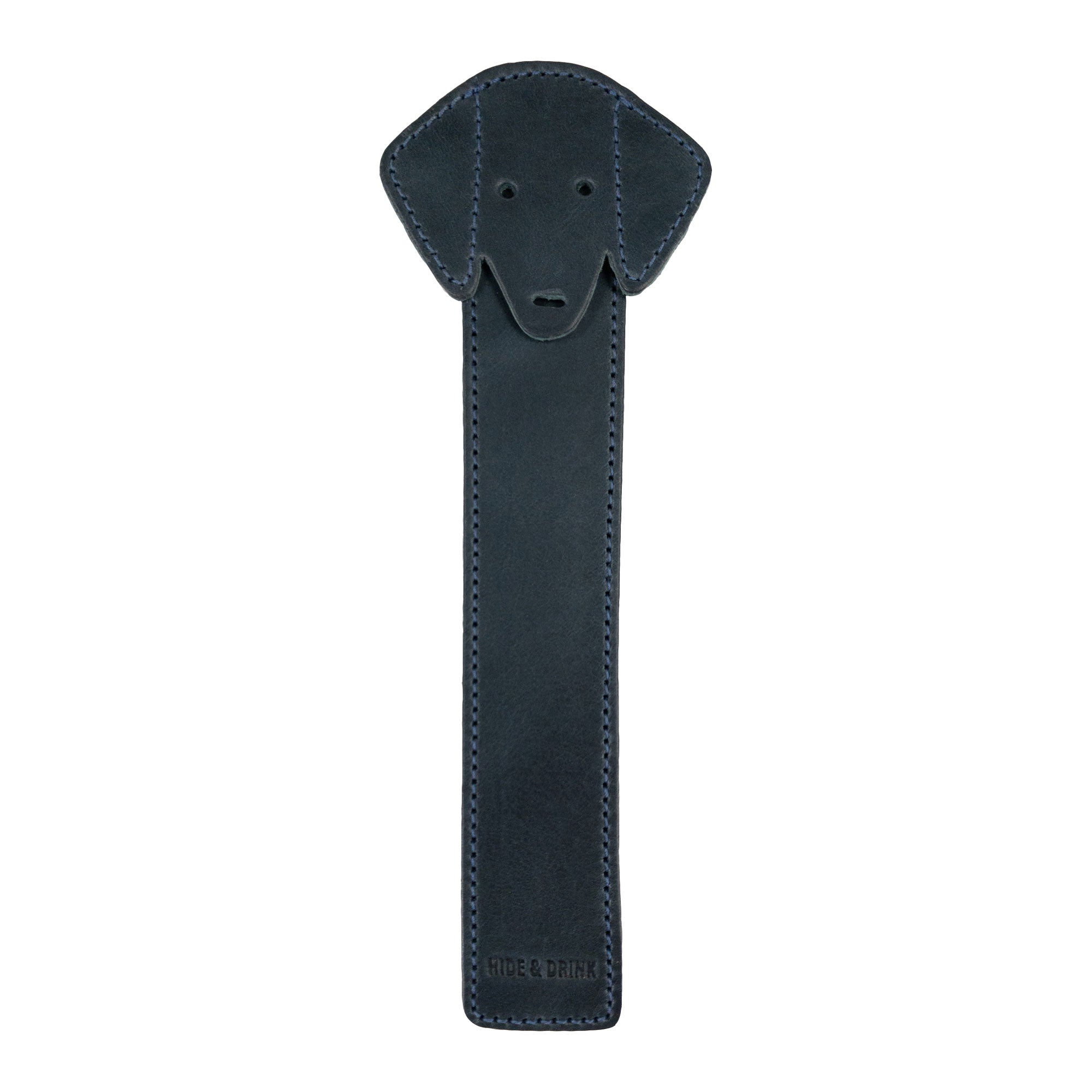 The front view of Hide & Drink's navy Dog Bookmark made from Full Grain Leather, showcasing its charming dog face design. This artisan bookmark is handcrafted with small batch production quality and fire branding from La Antigua Guatemala & Oaxaca Mexico.
