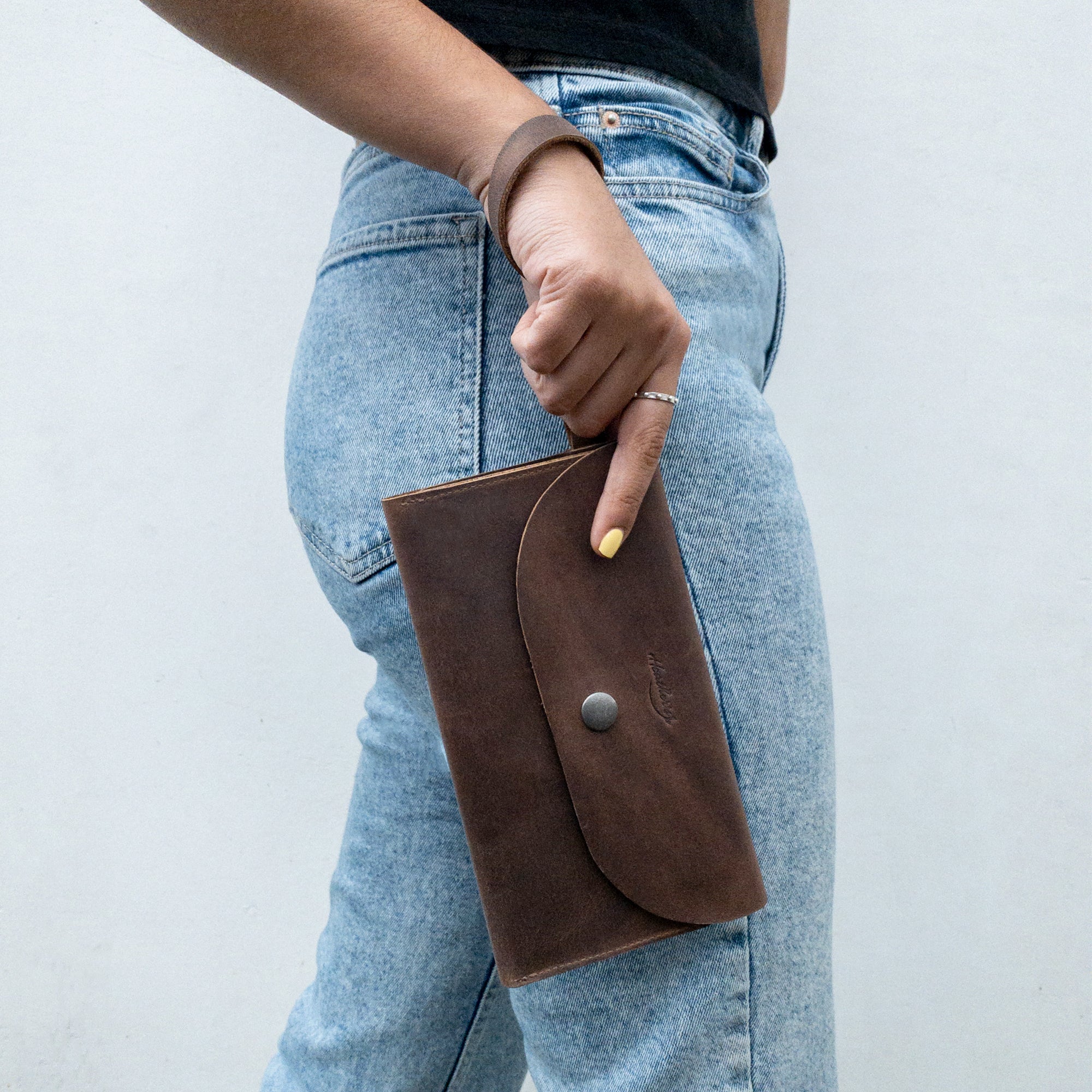 Woman holding Heather's Wallet with Wristlet, elegantly designed for women, perfect for on-the-go. This rectangular wallet features multiple card slots and is made from premium Full Grain Leather, ideal as a stylish travel accessory and money organizer. StockyardX, Small Batch Production, Hand Cut, Hand Sewn, Fire Branded, Artisan, Handmade in La Antigua Guatemala & Oaxaca Mexico.