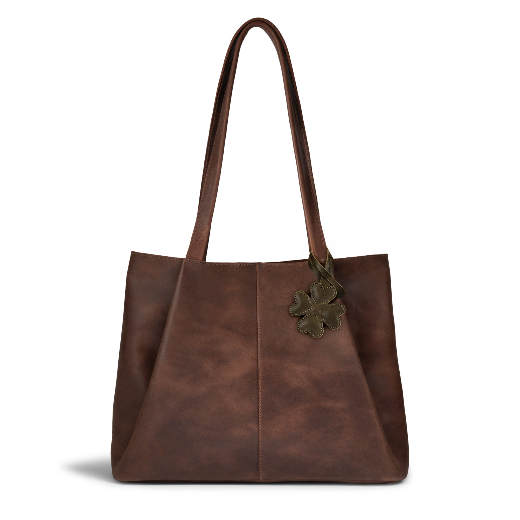 Stylish brown tote bag featuring the Hide & Drink Clover Bag Charm. This charming accessory enhances the bag's appeal, perfect for women looking for unique purse charms for handbags and backpacks. Made from full grain leather, this artisan piece is handcrafted in La Antigua Guatemala & Oaxaca Mexico.