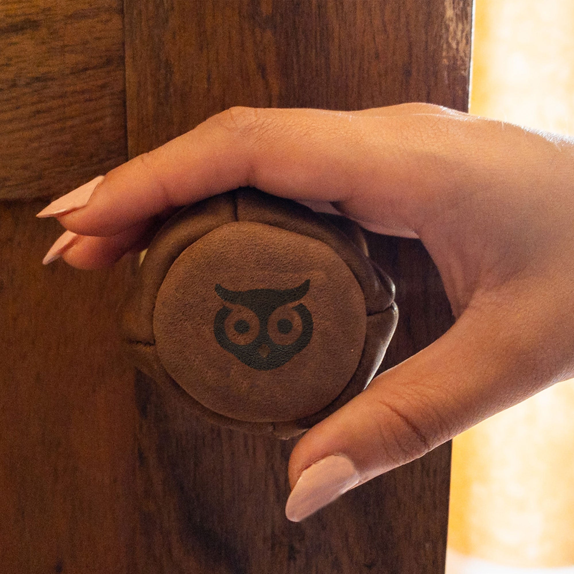 Hide & Drink's Door Knob Cover being held, displaying its practical and stylish design. Made from fine Full Grain Leather, this baby proof door knob cover is part of a small batch production, showcasing handmade quality and artisan craftsmanship from La Antigua Guatemala.