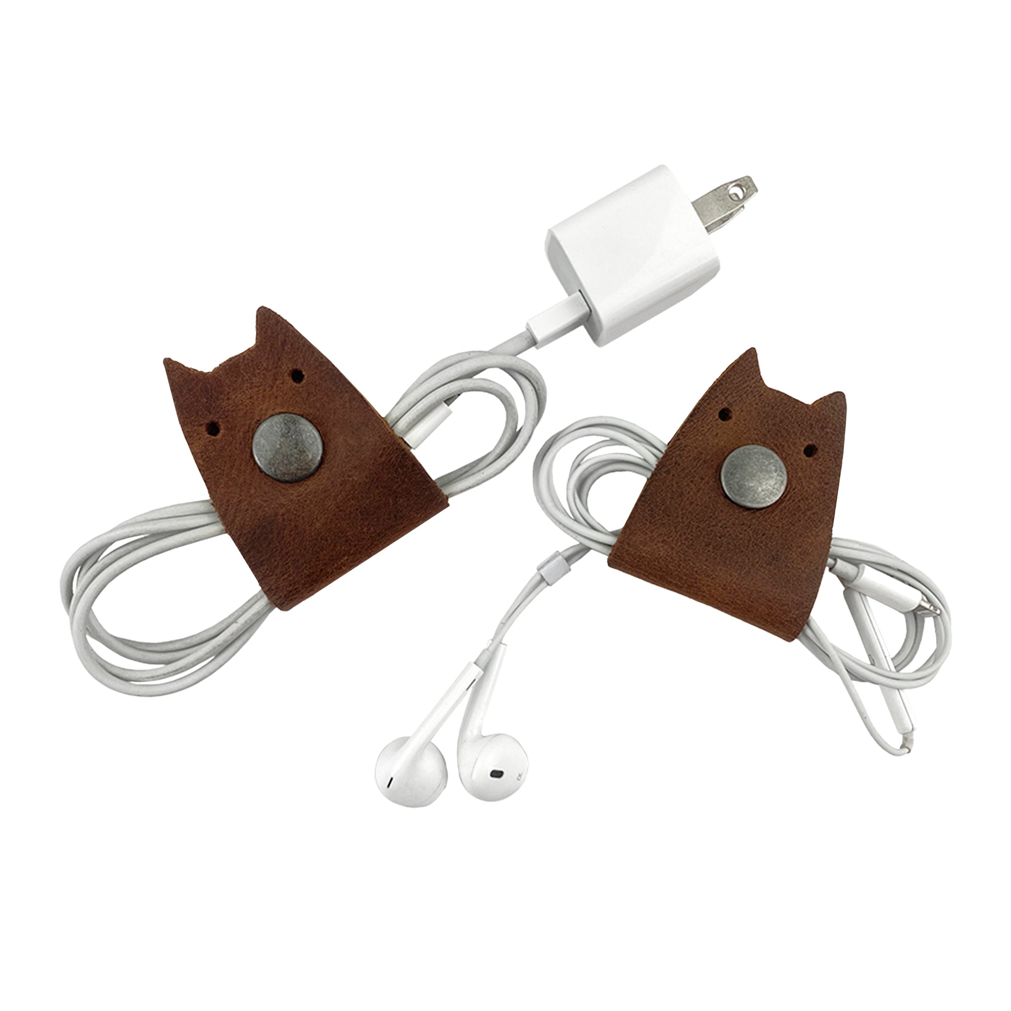 Taco Dog's Cat Cord Keeper (2 Pack) shown with cables wrapped neatly. These stylish cord keepers, made from full grain leather, keep your cables, earbuds, headphones, and chargers organized. Clip the snaps together for hassle-free travel. Expertly crafted with artisan techniques, each piece is handmade in La Antigua Guatemala & Oaxaca Mexico.
