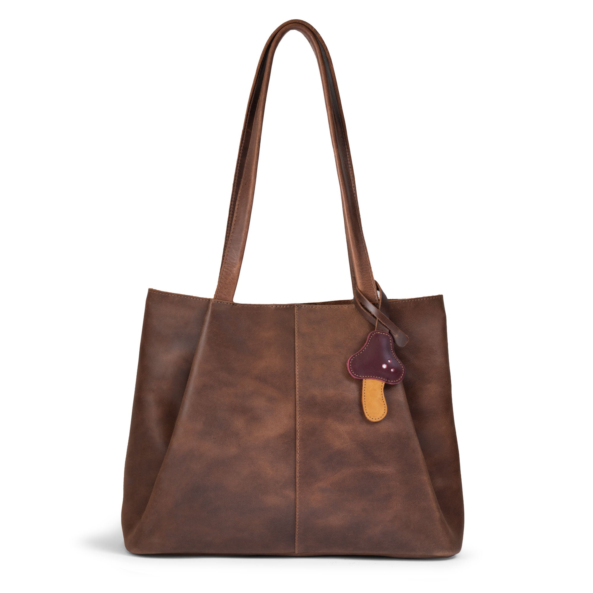 Hide & Drink Bag Charms attached to a trendy brown handbag, showcasing a pineapple design perfect for personalization. This purse charm for tote & backpacks made from premium full grain leather reflects StockyardX's commitment to small batch production. Each piece highlights hand cut, hand sewn craftsmanship along with fire branding, handmade in La Antigua Guatemala & Oaxaca Mexico.