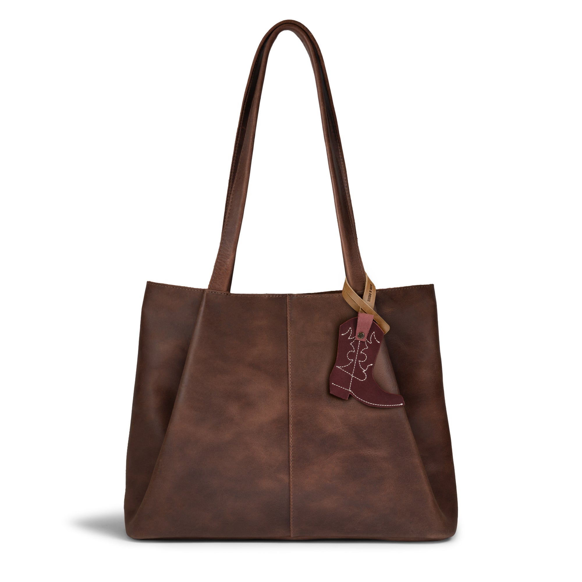 The Western Boot Bag Charm by Hide & Drink adds a stylish touch to your brown leather tote, showcasing the perfect blend of artisan craftsmanship and full grain leather. Ideal as a purse charm or backpack ornament for women, it's handmade in La Antigua, Guatemala & Oaxaca, Mexico, combining small batch production with hand cut and hand sewn details.
