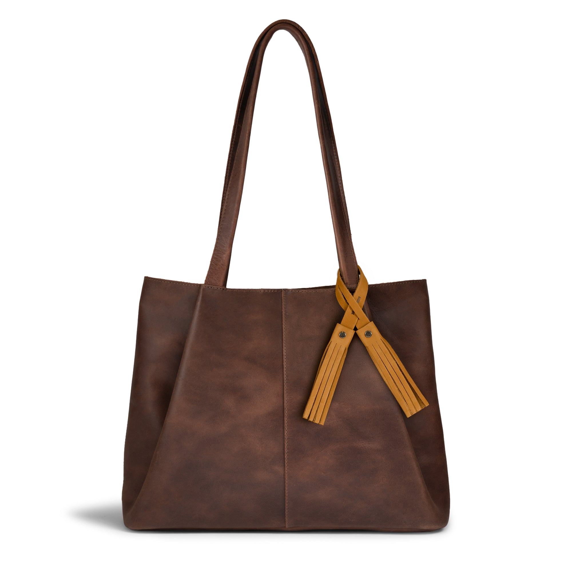 The Tassel Bag Charm Old Tobacco by Hide & Drink elegantly attached to a brown leather handbag. This full grain leather charm serves as a purse charm for totes and backpacks, enhancing your accessories with its unique design. Handcrafted in small batch production, it reflects artisan techniques such as fire branding and meticulous hand sewing, embodying the spirit of craftsmanship from La Antigua Guatemala and Oaxaca, Mexico.
