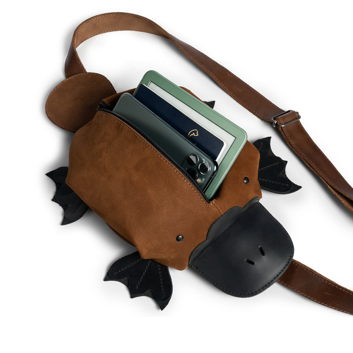 Tudi Frudi Platypurse Crossbody Bag open with a wallet, phone, and essentials inside, highlighting its Adjustable Shoulder Strap, Zippered Sling Bags functionality, Messenger Bag and Shoulder Bag design, Travel Backpack versatility, Purses for Men and Women appeal, Satchel shape, Swayze Suede and Full Grain Leather construction, StockyardX Small Batch Production, Hand Cut and Hand Sewn Artisan craftsmanship, Fire Branded detail, Handmade in La Antigua Guatemala & Oaxaca Mexico.