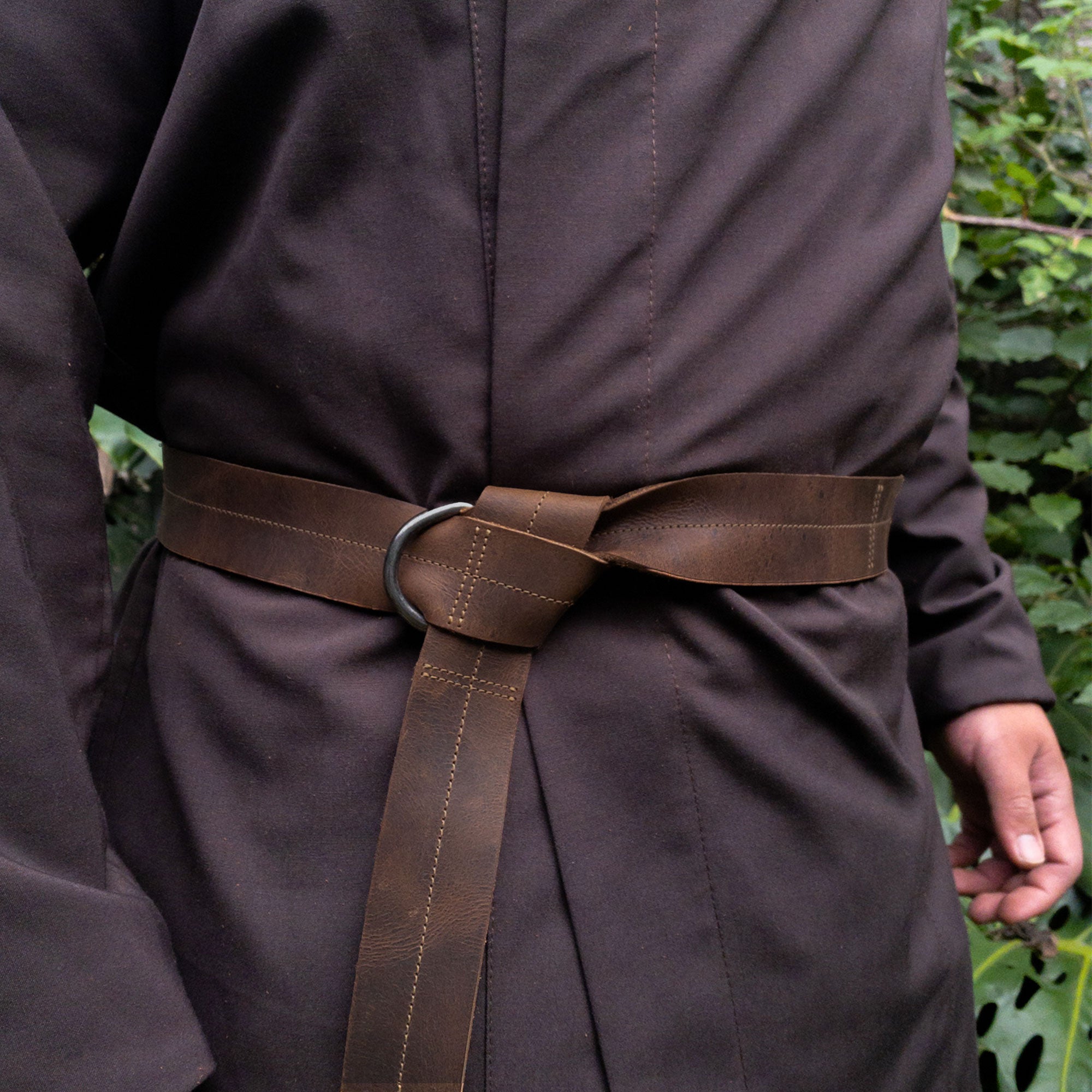 A model wearing the Medieval Belt with Stitching from Valhalla Gear, demonstrating its half-ring closure in action. This stylish Medieval Belt for Men with Stitching, ideal for cosplay and reenactments, is made of durable full grain leather, showcasing the artisan craftsmanship of handmade production in La Antigua Guatemala & Oaxaca Mexico.