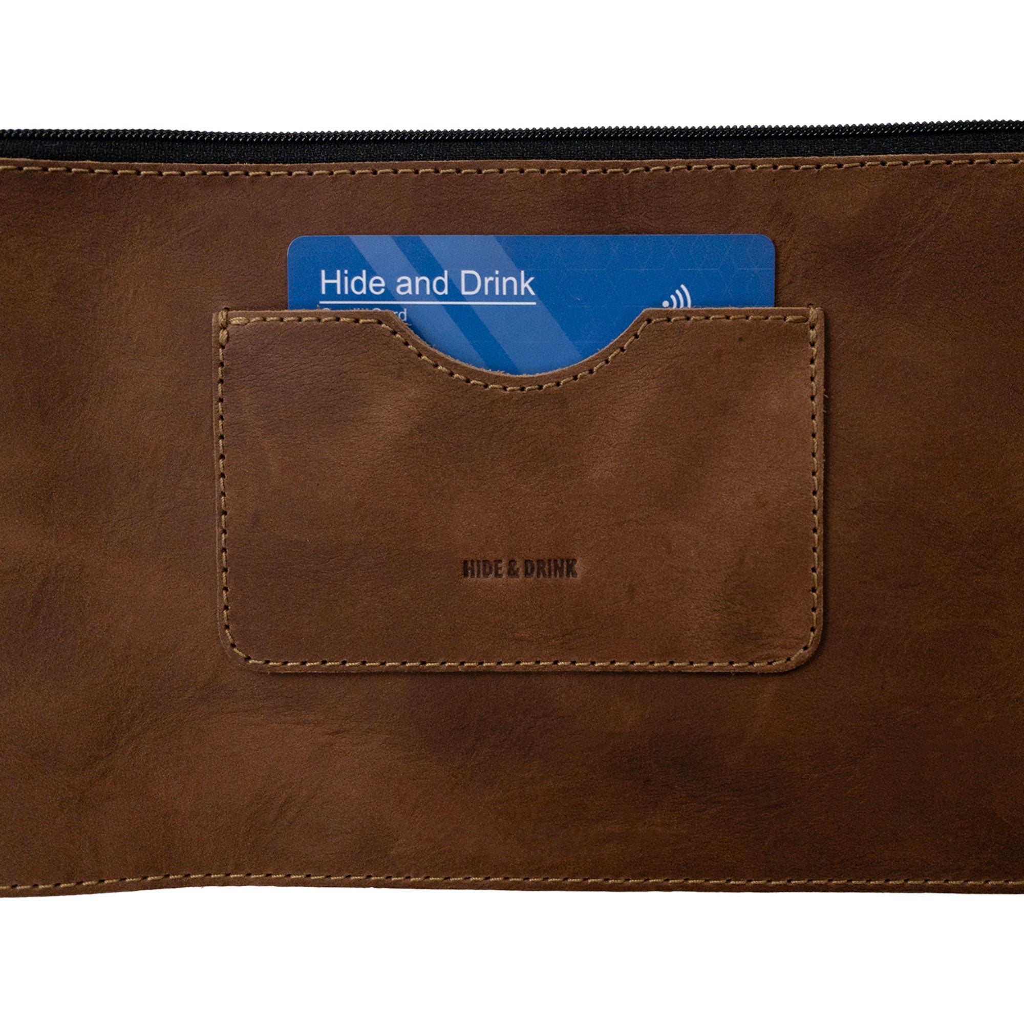Close-up of a brown rectangular zippered handbag by Hide & Drink showing the card slot. This female purse is handcrafted from durable full grain leather, showcasing knead excellence with small batch production techniques while being handmade in La Antigua Guatemala & Oaxaca Mexico.