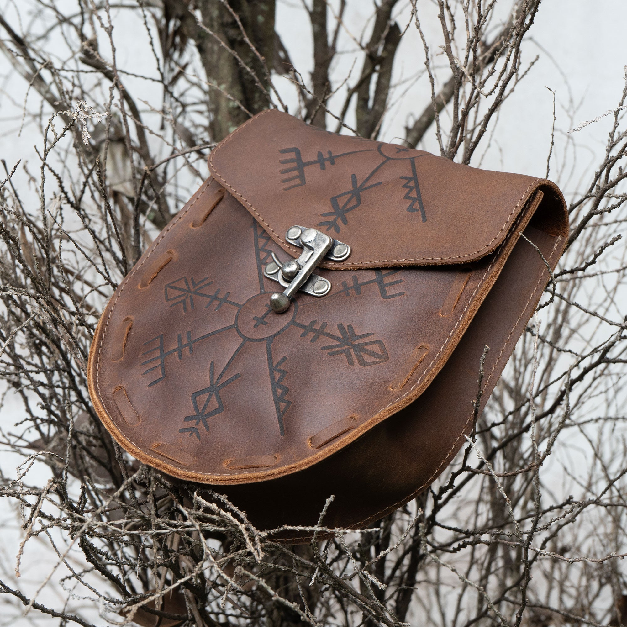 Rune Belt Pouch from Hide & Play, showcasing a beautiful medieval style waist bag perched on a branch. Handcrafted from full grain leather, this Viking waist bag is ideal for costume parties and LARPing, made with care in La Antigua Guatemala through artisan methods including fire branding.