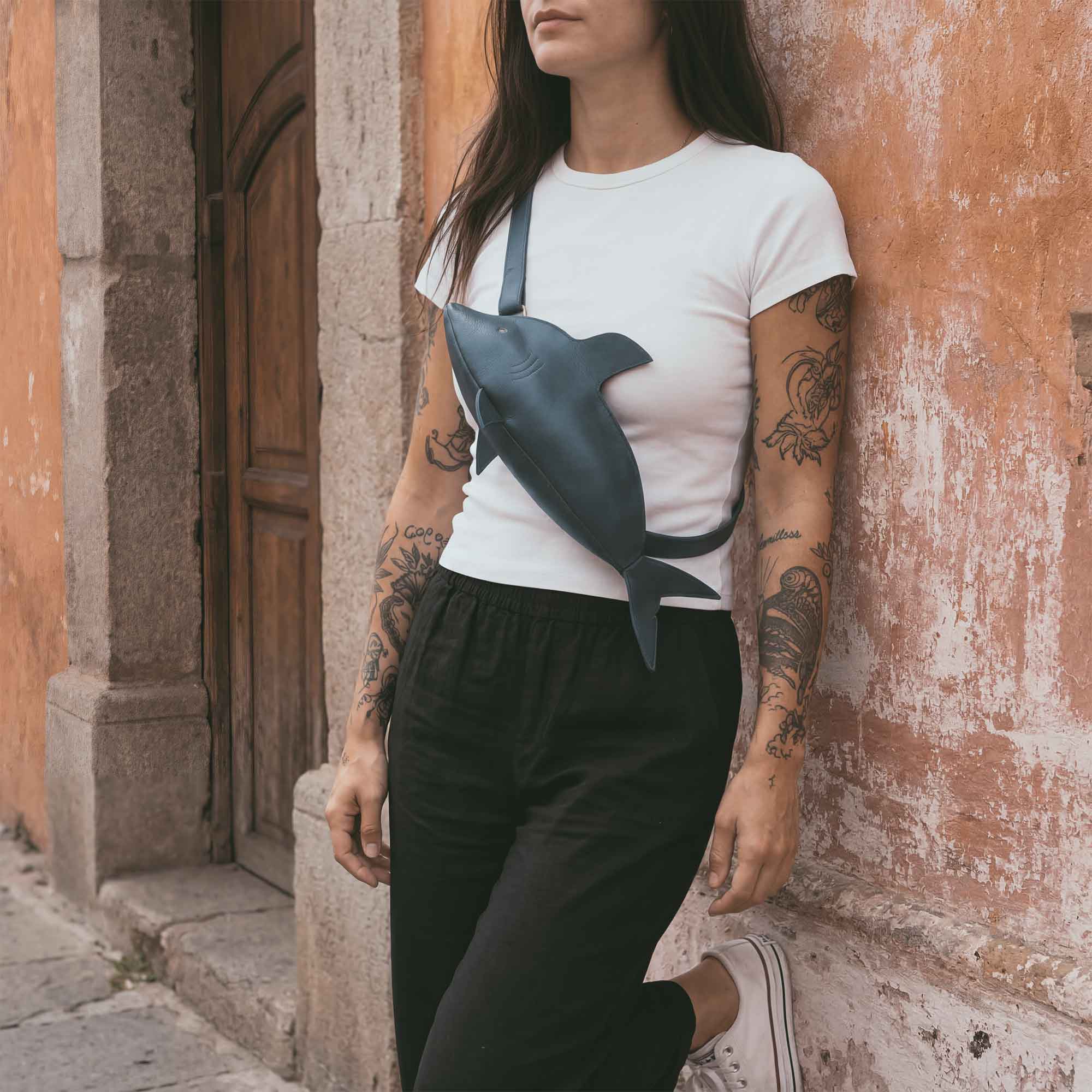 Model wearing the Shark-Shaped Crossbody by Tudi Frudi, a standout Leather Shark-Shaped Sling Bag with Adjustable Strap. This chic Crossbody Purse is ideal for women and offers versatility as a Fanny Pack or Shoulder Travel Bag. Hand cut and hand sewn, it represents small batch production from La Antigua Guatemala, showcasing artisan quality.