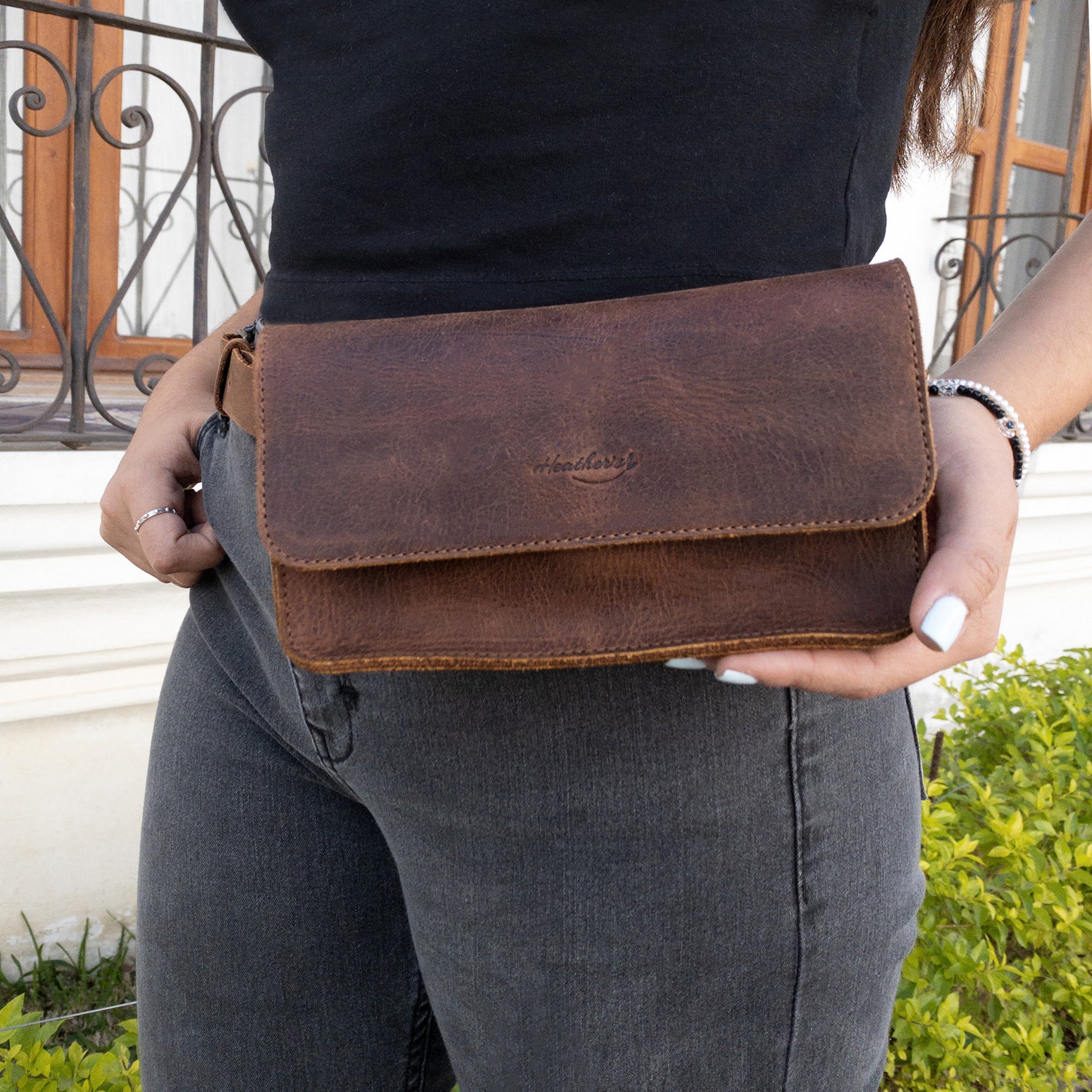 Heather's Rectangular Fanny Pack worn by a woman, highlighting its functional and chic design. This hip bag with an adjustable strap serves as a versatile waist pouch, made from full grain leather. Each piece is hand cut and hand sewn, ensuring quality and uniqueness, made in La Antigua Guatemala & Oaxaca Mexico.