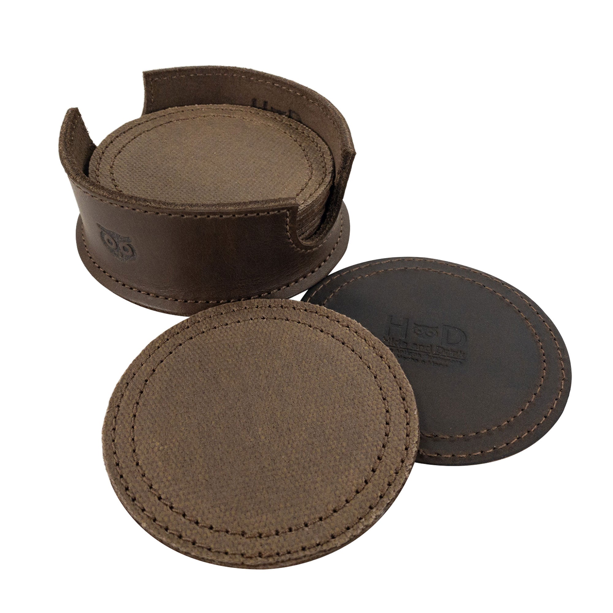 A single brown circular coaster displayed on its holder from the Set of 8 Circular Coasters for Drinks by Hide & Drink. Perfect for Glass & Cups Stain Protection, this handmade item is crafted from durable Waxed Canvas and Full Grain Leather. Enjoy the artistry of StockyardX with these Small Batch Production pieces, which are Hand Cut, Hand Sewn, Fire Branded, and made Artisan, Handmade in La Antigua Guatemala & Oaxaca Mexico.