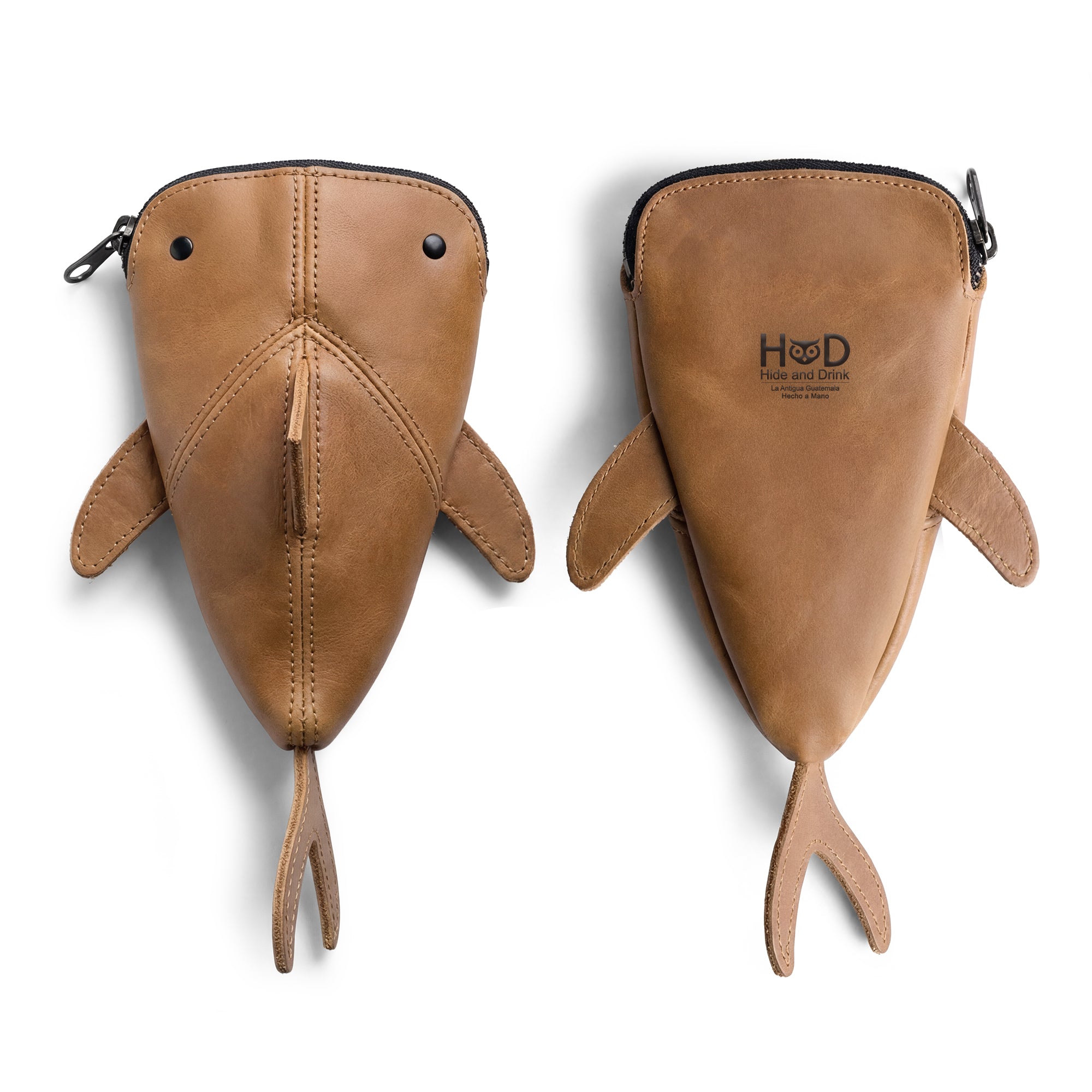 Two views of the Hide & Drink Leather Shark Pouch reveal its meticulous design and craftsmanship. This shark-shaped zippered pouch is perfect as a change bag or pencil purse, embodying the essence of small batch production. Made from full grain leather and hand sewn by artisans in La Antigua Guatemala & Oaxaca Mexico, it’s a unique storage solution.