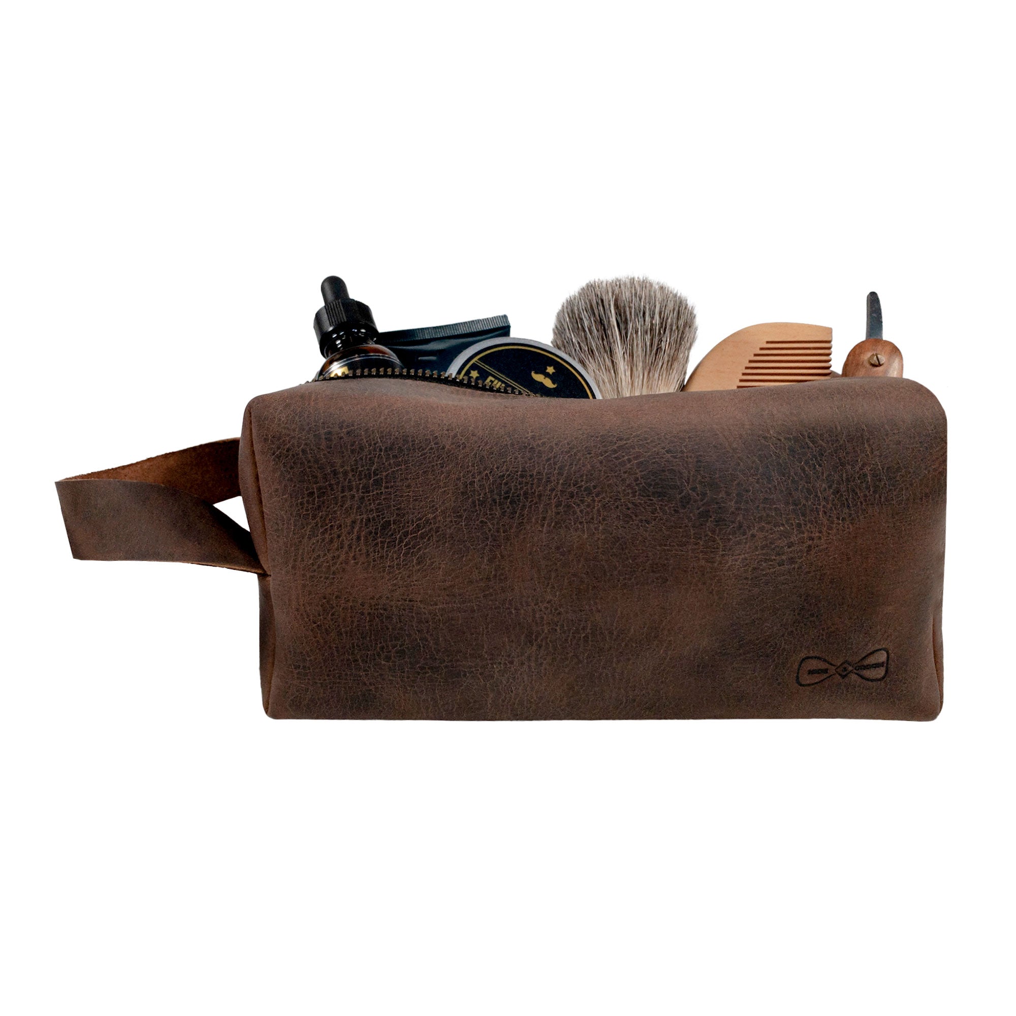 Side view of Hide & Groom's toiletry bag for groomsmen, demonstrating its spacious interior filled with grooming tools. This handcrafted rustic bag, made from full grain leather, is designed for best men at wedding ceremonies as a reliable bathroom bag reflecting artisan quality.