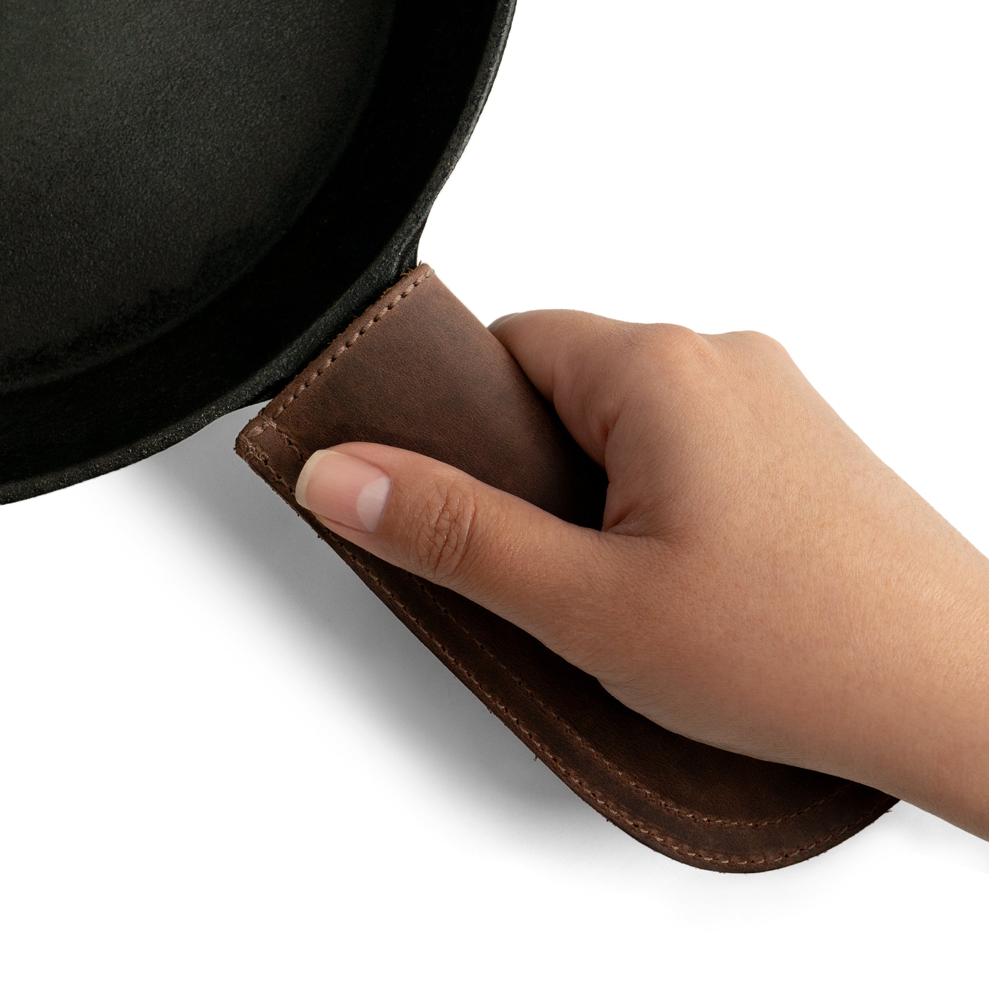 Hide & Drink Cast Iron Panhandle Cover presented artistically, showcasing its craftsmanship. This artisan hot handle protector is designed from durable full grain leather with double stitching for optimal strength. Handmade in La Antigua Guatemala & Oaxaca Mexico, it's a kitchen essential for any cooking enthusiast.