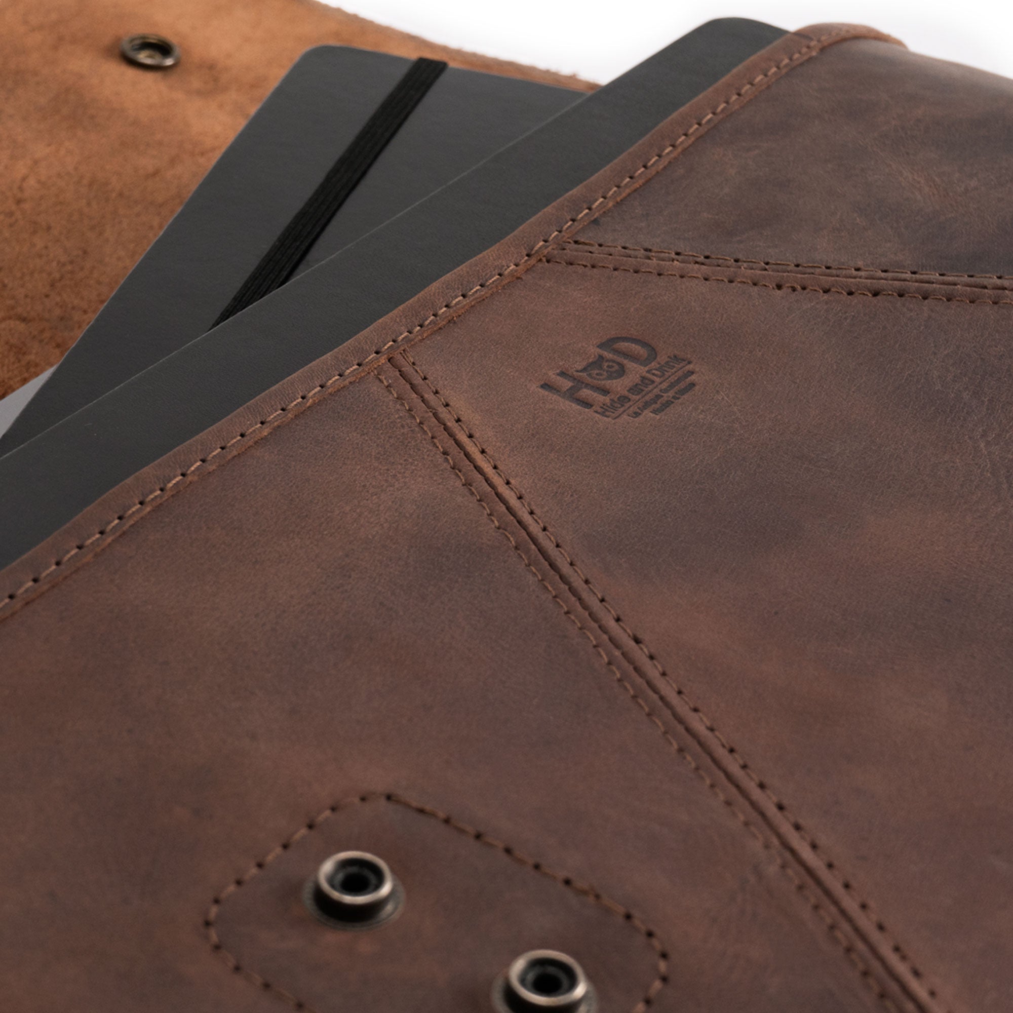 Detailed view of Hide & Drink's Vintage Folder Holder XL, emphasizing the superior Full Grain Leather and fire branded logo. This unique leather folder serves as a sophisticated office accessory, suitable for organizing documents and as a padfolio. Each holder is hand cut and sewn by artisans in La Antigua Guatemala and Oaxaca Mexico.