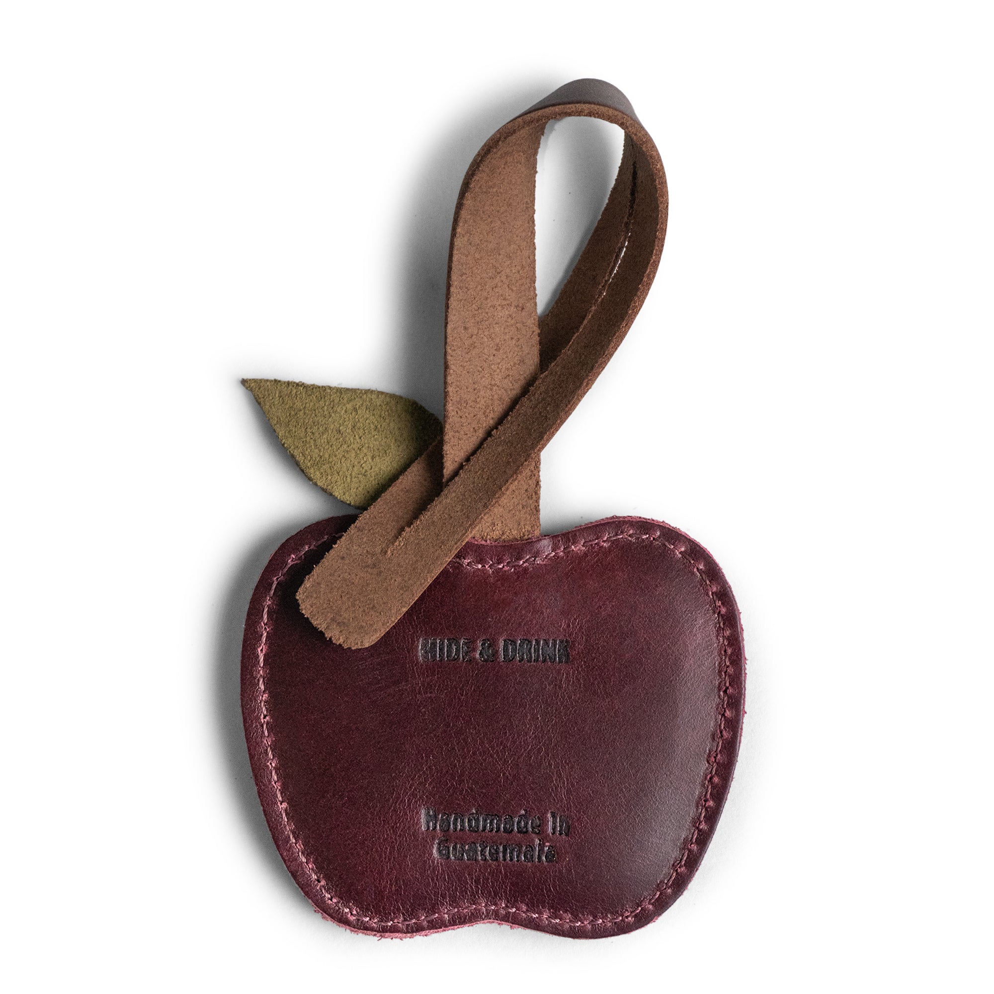 Close-up of the Hide & Drink Apple Bag Charm, highlighting the fire-branded logo and leather leaf detail. This artisan charm is crafted from full grain leather and serves as a perfect accessory for tote bags and purses, handmade in La Antigua Guatemala and Oaxaca Mexico.