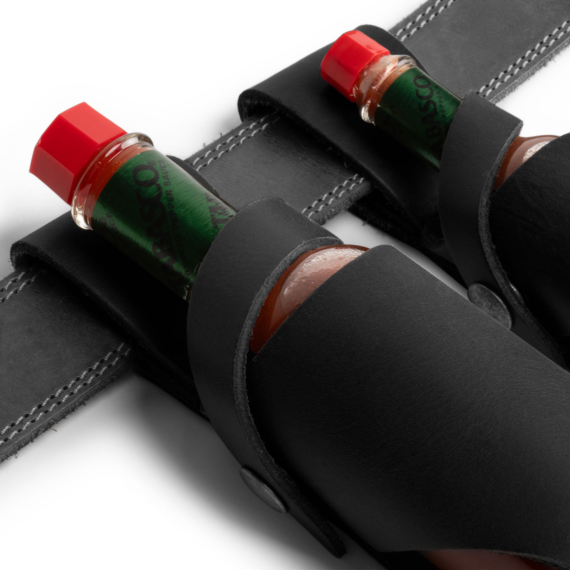 Hide & Drink Tabasco Holsters (2pk) showcasing finely designed holders for 5oz and 2oz hot sauce bottles. Excellent for Tabasco and Cholulah, made from robust full grain leather, these holsters reflect artisan quality and small batch production from La Antigua Guatemala & Oaxaca Mexico.