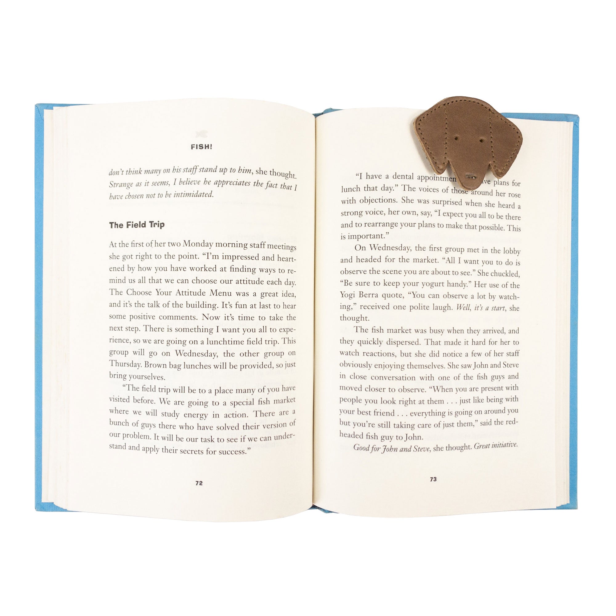 Close-up of Hide & Drink's tan Dog Bookmark in use, adding a charming touch to a book with its Full Grain Leather make. This handmade bookmark reflects the quality of small batch production and fire branding from La Antigua Guatemala & Oaxaca Mexico.