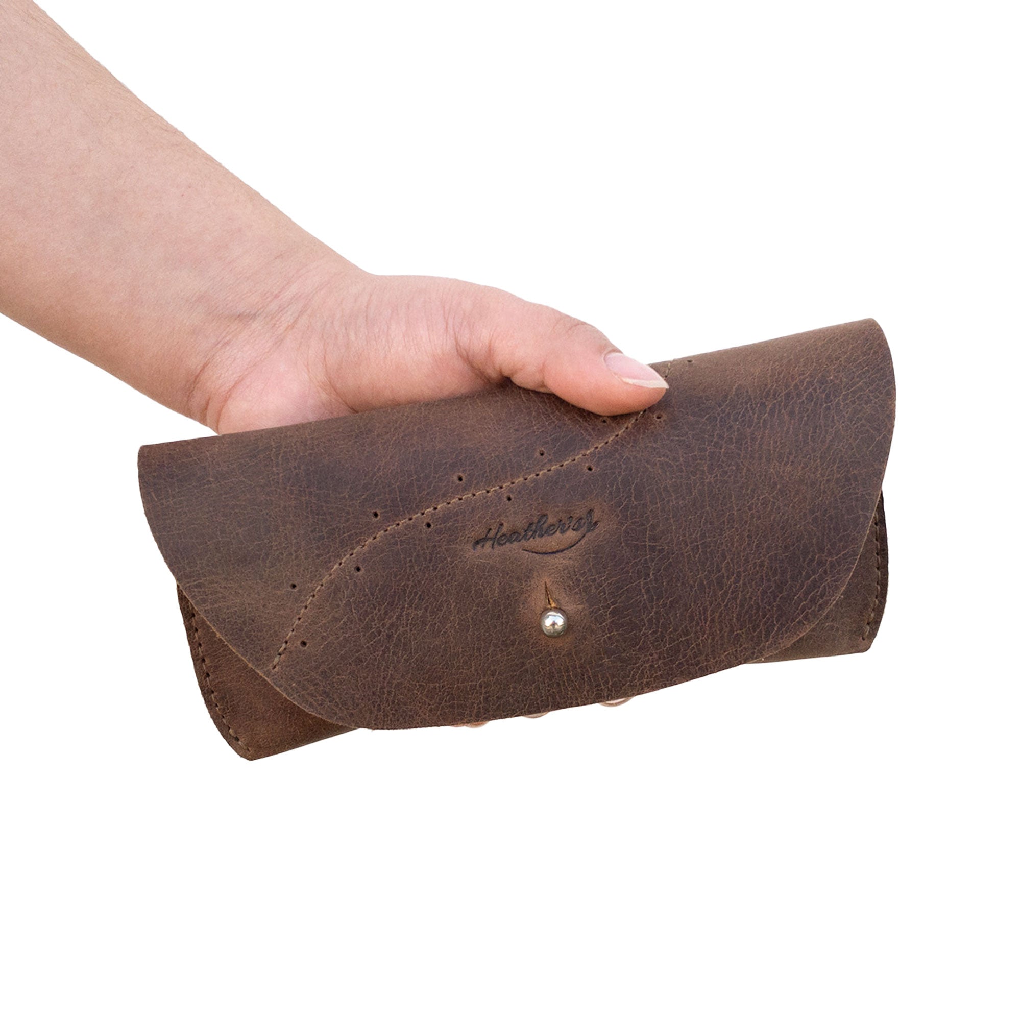 A hand holding Heather's Eyeglasses Case, demonstrating its compact size and elegant handmade design. This full grain leather eyewear protector offers safe storage for travel while reflecting the artisan quality of StockyardX products.