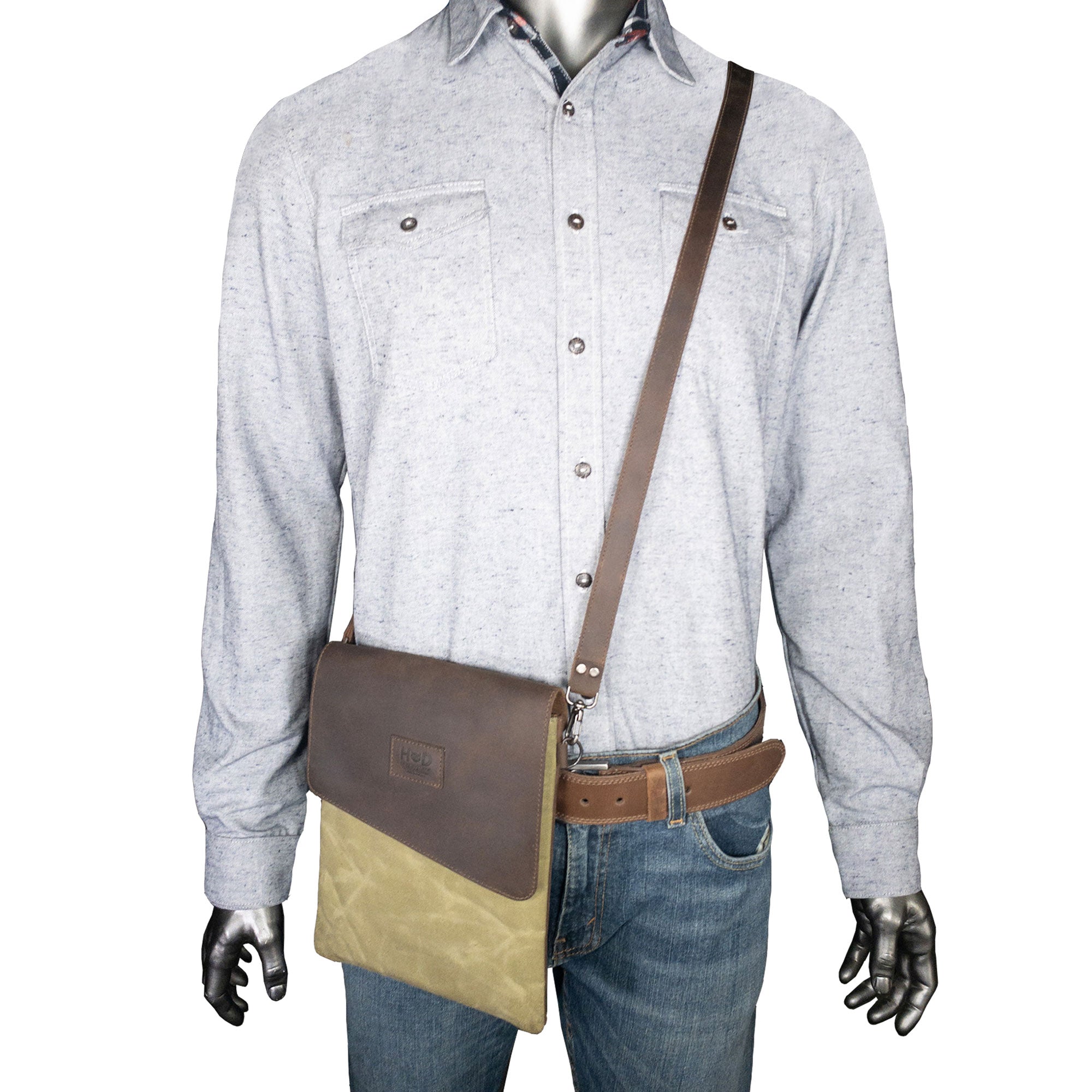 Hide & Drink Crossbody Bag worn across the body by a mannequin in casual attire. This Crossbody Bag with Adjustable Shoulder Strap is a Unisex Messenger Bag made from premium Full Grain Leather & Waxed Canvas, demonstrating small batch production, hand cut, hand sewn, fire branded techniques from artisans in La Antigua Guatemala & Oaxaca Mexico.