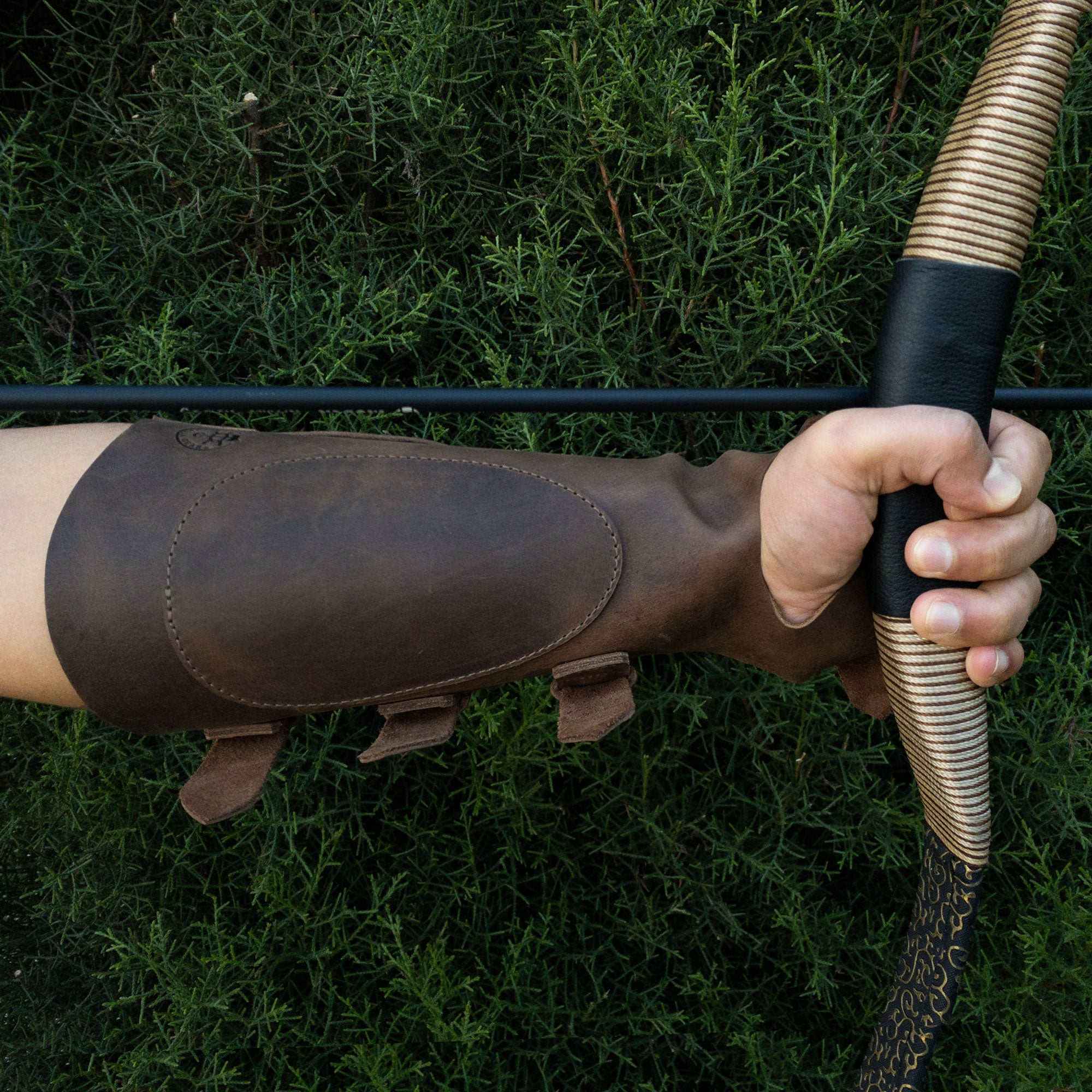 A close-up shot of the Archery Bracer with Thumb Slot from Valhalla Gear, highlighting its sleek design suitable for archers and knights. This leather wrist guard ensures a secure fit with adjustable buckle straps, enhancing its functionality for cosplay and events. Handcrafted in La Antigua Guatemala, this artisan piece represents small batch production.