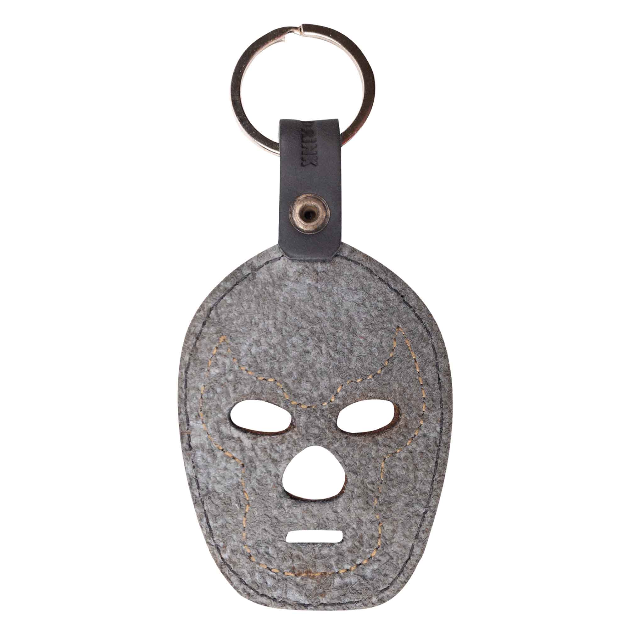 The Luchador Mask Leather Keychain displayed on a keyring, highlighting its practical design as a key organizer. This keyring by Hide & Drink is made from full grain leather and represents artisanal craftsmanship, emphasizing small batch production, hand cut and sewn by artisans in La Antigua Guatemala and Oaxaca Mexico.