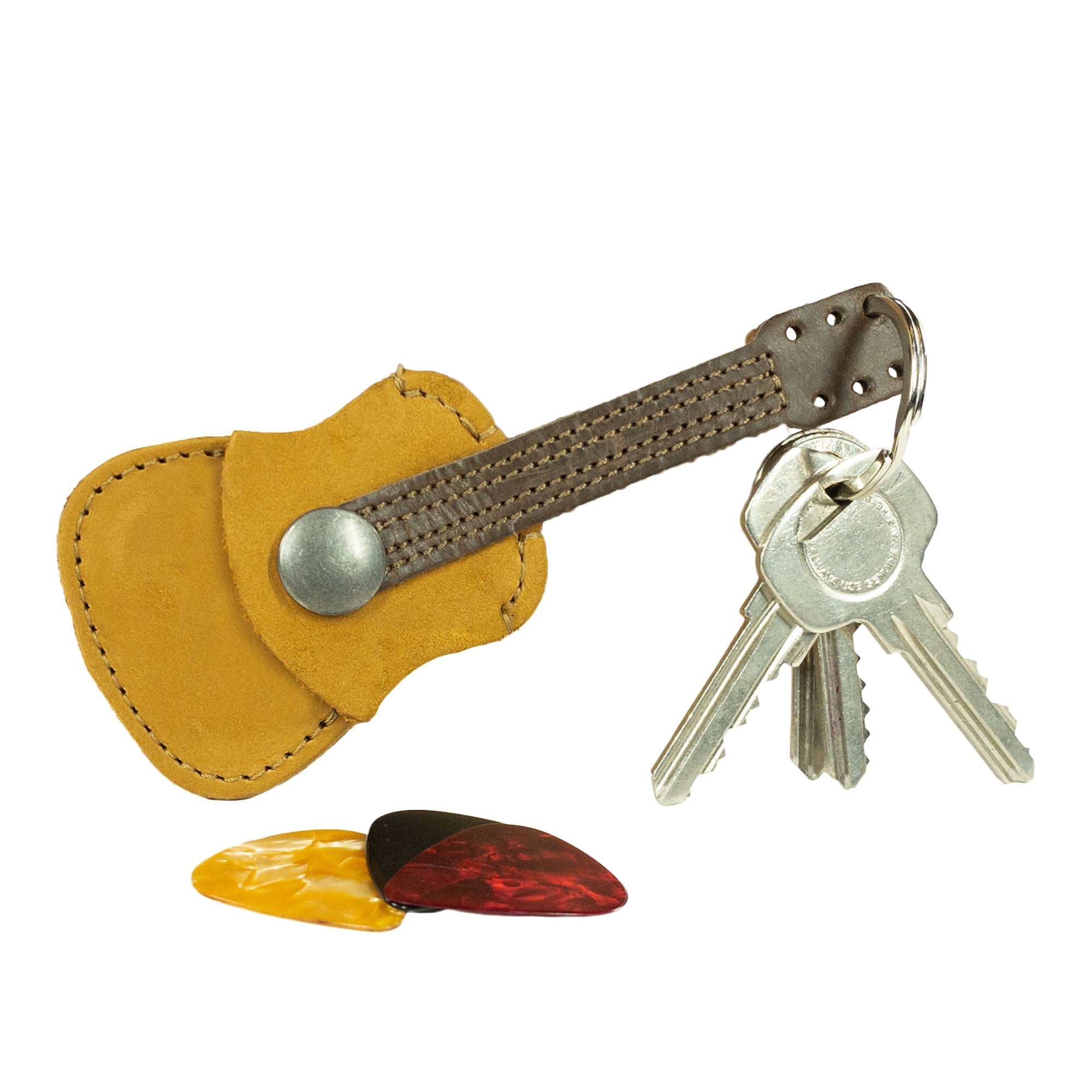 Hide & Drink Guitar Pick Holder alongside guitar picks, showcasing its versatility as a Leather Guitar Pick Holder Keychain. Ideal picks case instrument gift idea for musicians, made from full grain leather in small batch artisan production.