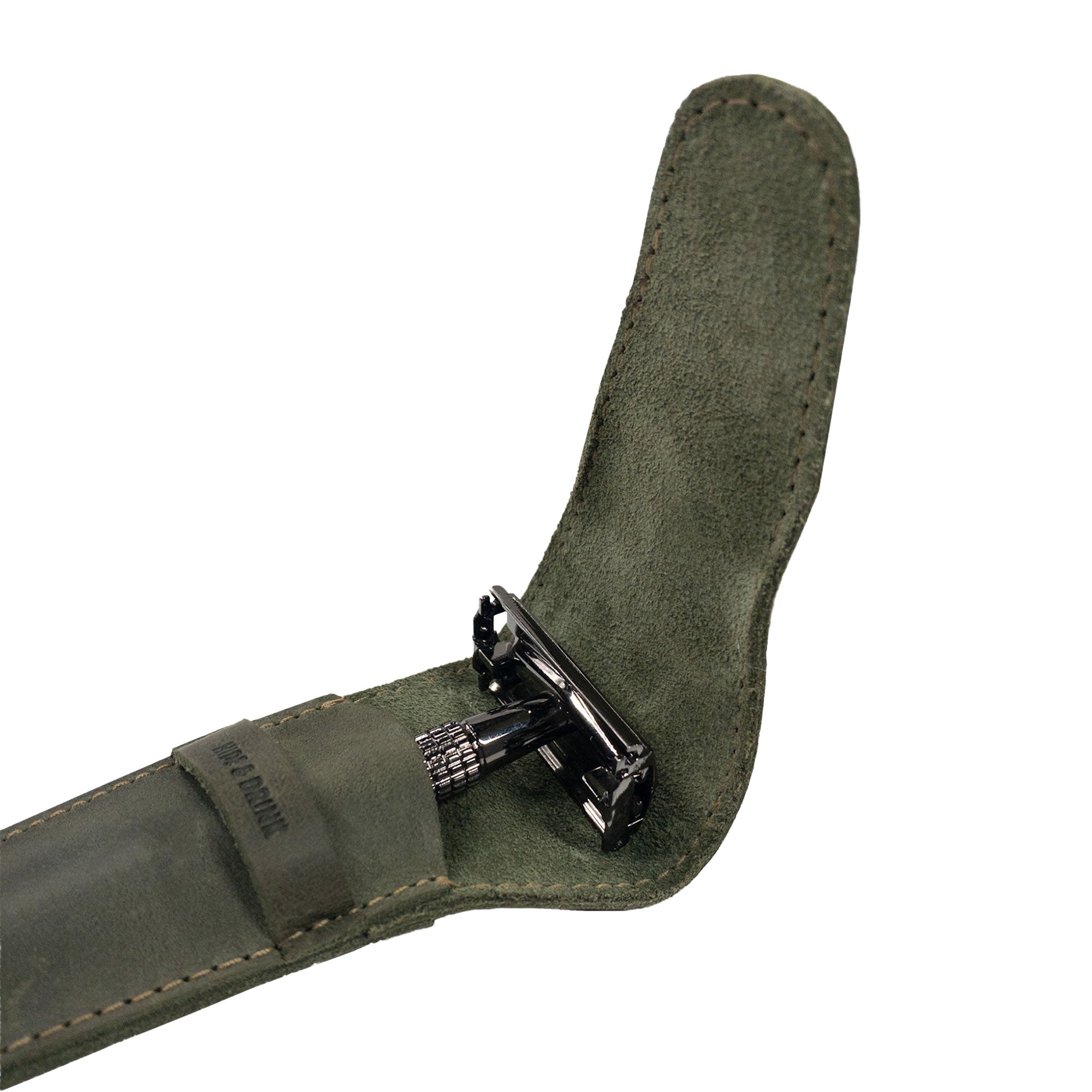 Close-up of the inside of the green Hide & Drink Safety Razor Case showing a razor, emphasizing the artisan details in this shaving accessory.