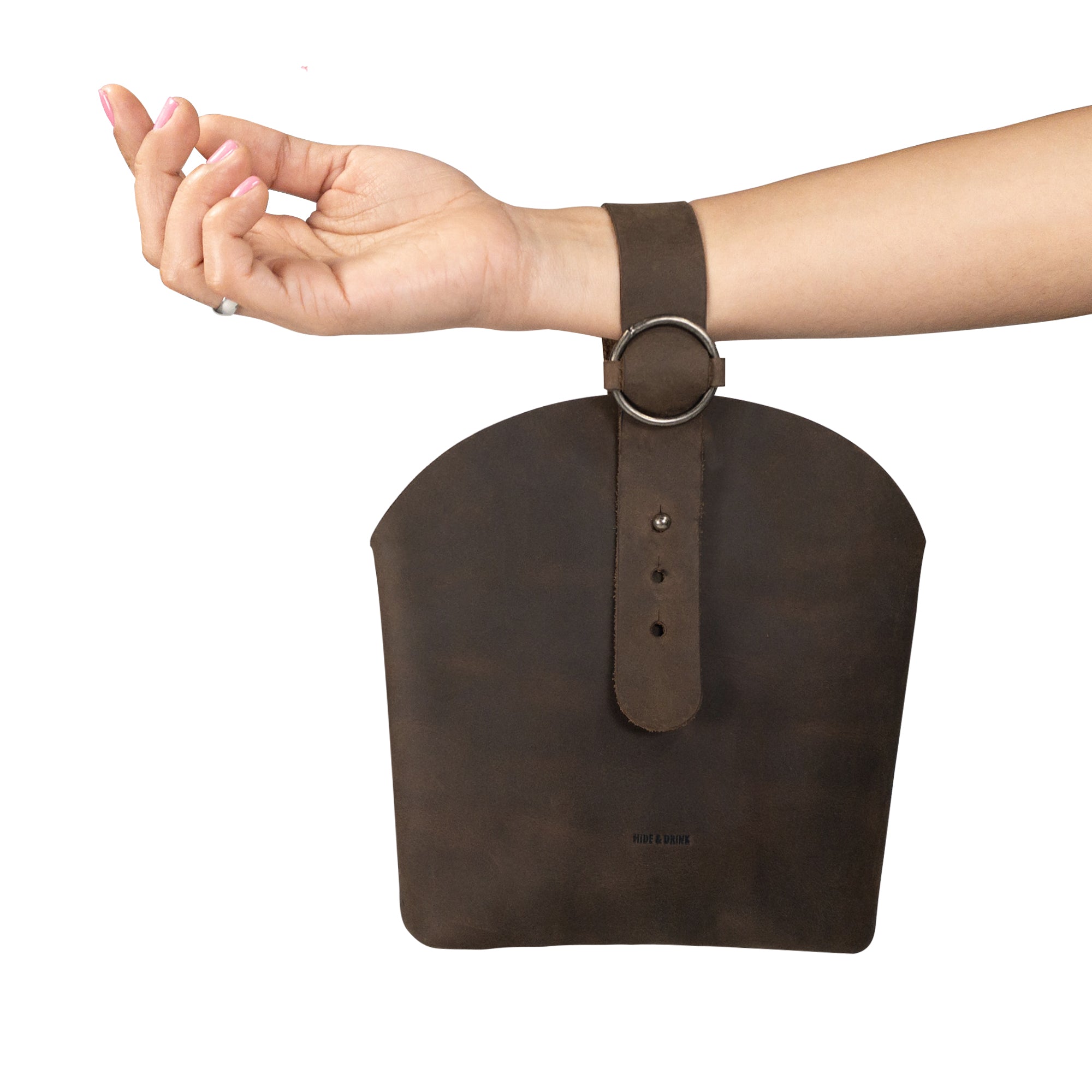 A person holding the Rounded Handbag by Hide & Drink, illustrating its versatility and stylish appeal as a travel organizer. Crafted from premium full grain leather, this handmade bag features artisan details with a commitment to small batch production and fire branded uniqueness, handmade in La Antigua Guatemala & Oaxaca Mexico.