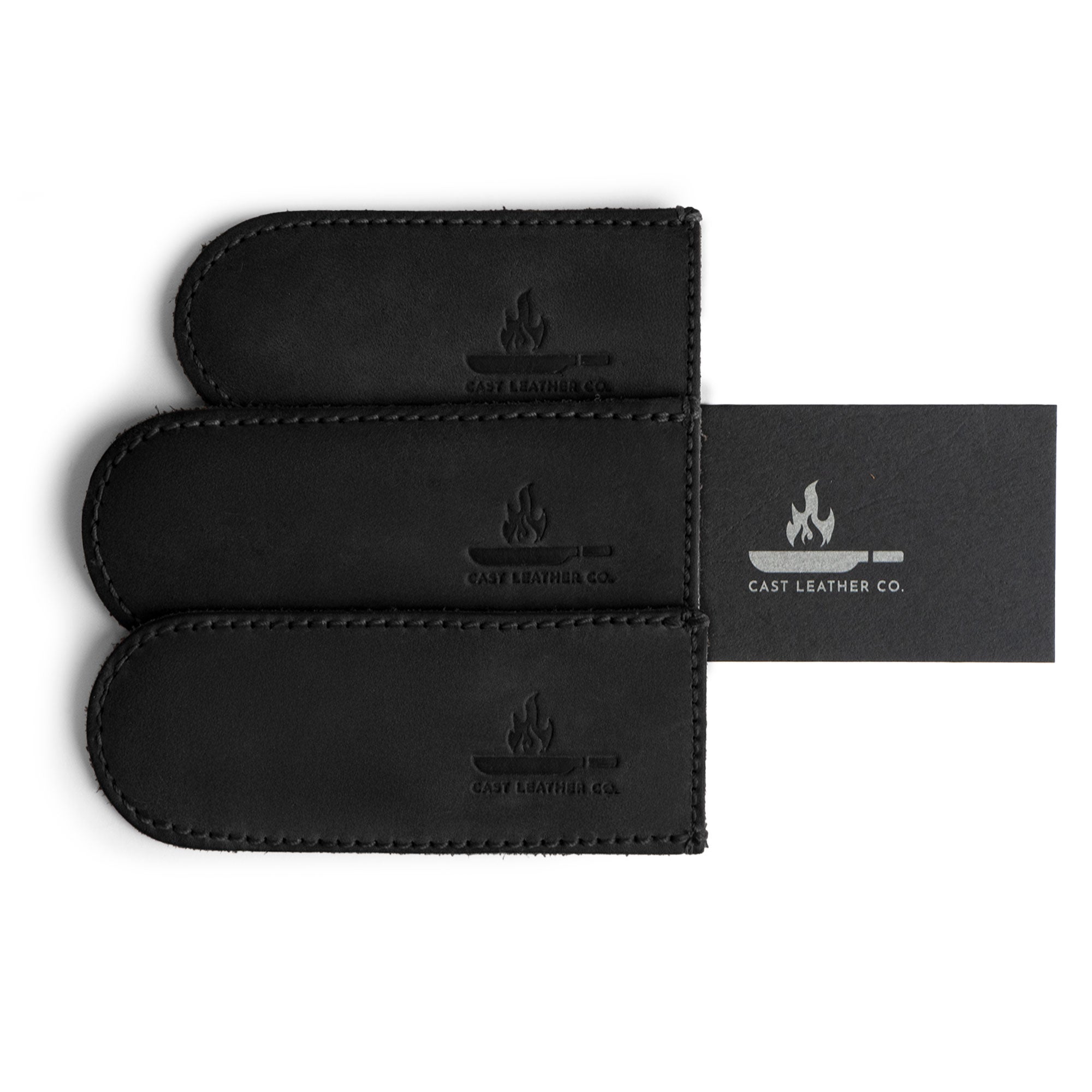 The black Hot Handle Covers (Set of 3) from Cast Leather Co. displayed with included business card, highlighting handmade quality. These full grain leather skillet handle covers combine functionality with style, showcasing the brand's commitment to artisan craftsmanship.