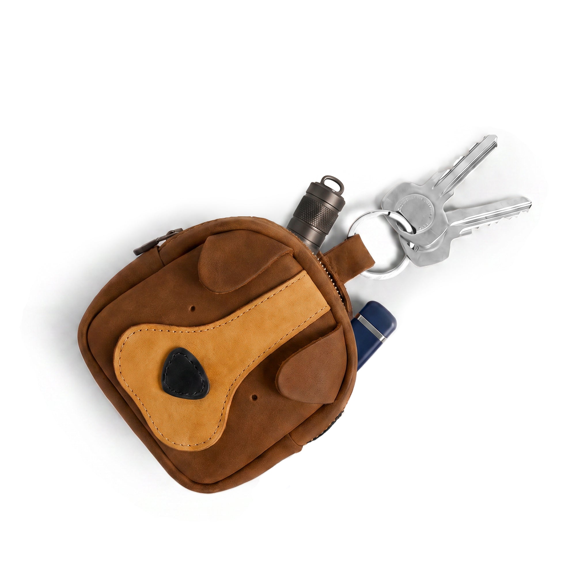 The Pouty Pup Mini Pack by Hide & Drink is seen from above, packed with keys and small essentials, showcasing its functionality as a mini wallet and cable pouch. This artisan-made accessory is crafted with care in La Antigua Guatemala, blending style and practicality seamlessly.