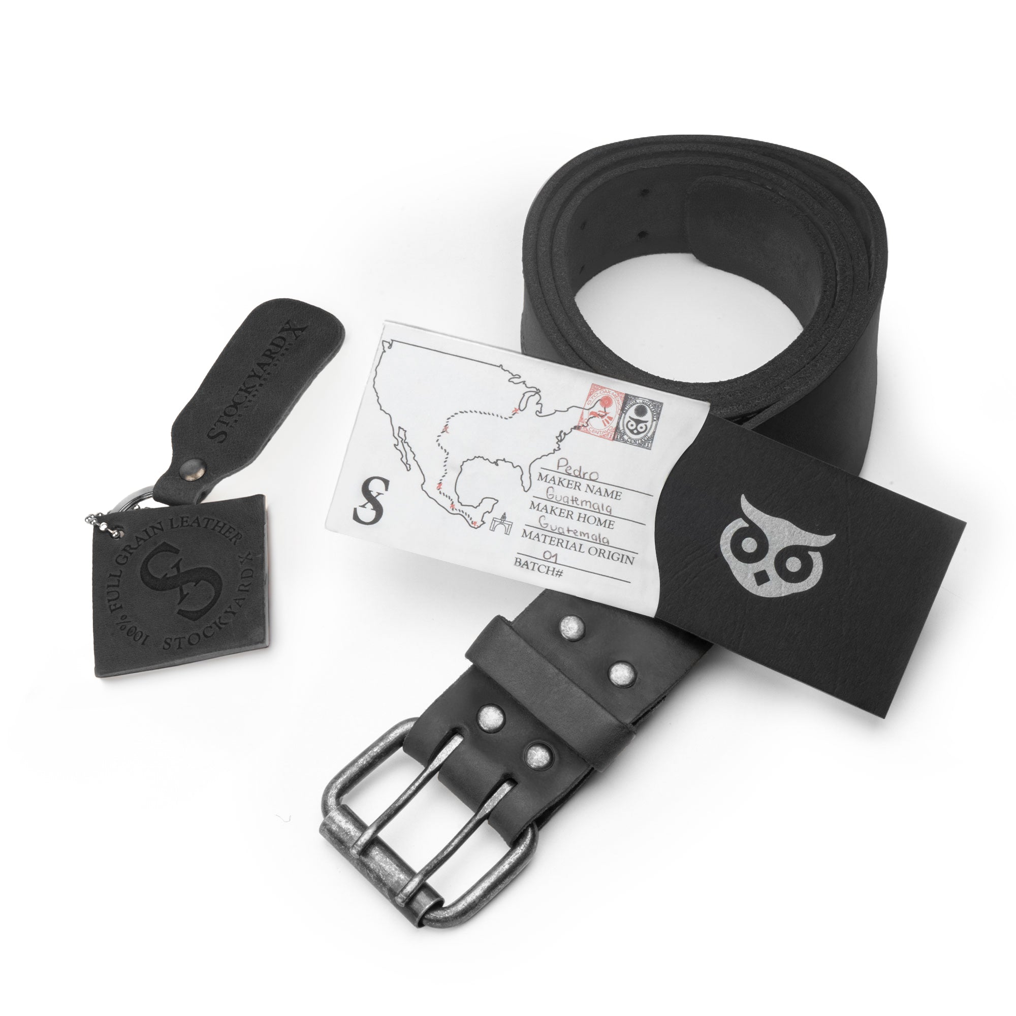 Showcasing the black Reinforced Double Prong Buckle Belt by Hide & Drink with its packaging, emphasizing its rugged design. This belt measures 1.5 in. wide and is made from full grain leather, showcasing stockyardX craftsmanship through small batch production, with details on its hand cut, hand sewn, and fire branded artisan methods, made in La Antigua Guatemala & Oaxaca Mexico.