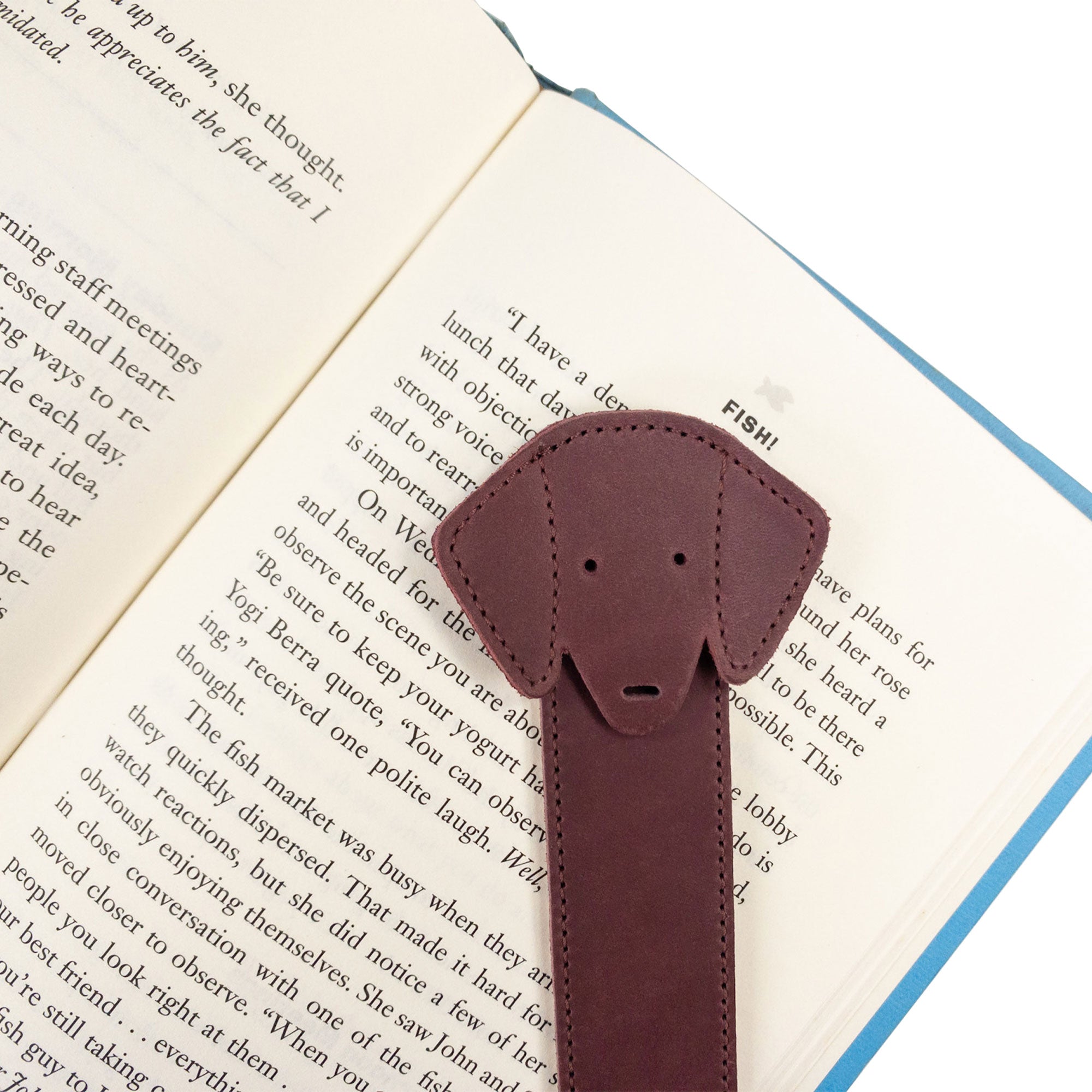 Close-up of Hide & Drink's burgundy Dog Bookmark resting on a book, emphasizing its Full Grain Leather quality. This artisan bookmark exemplifies small batch production and fire branding, crafted in La Antigua Guatemala & Oaxaca Mexico.
