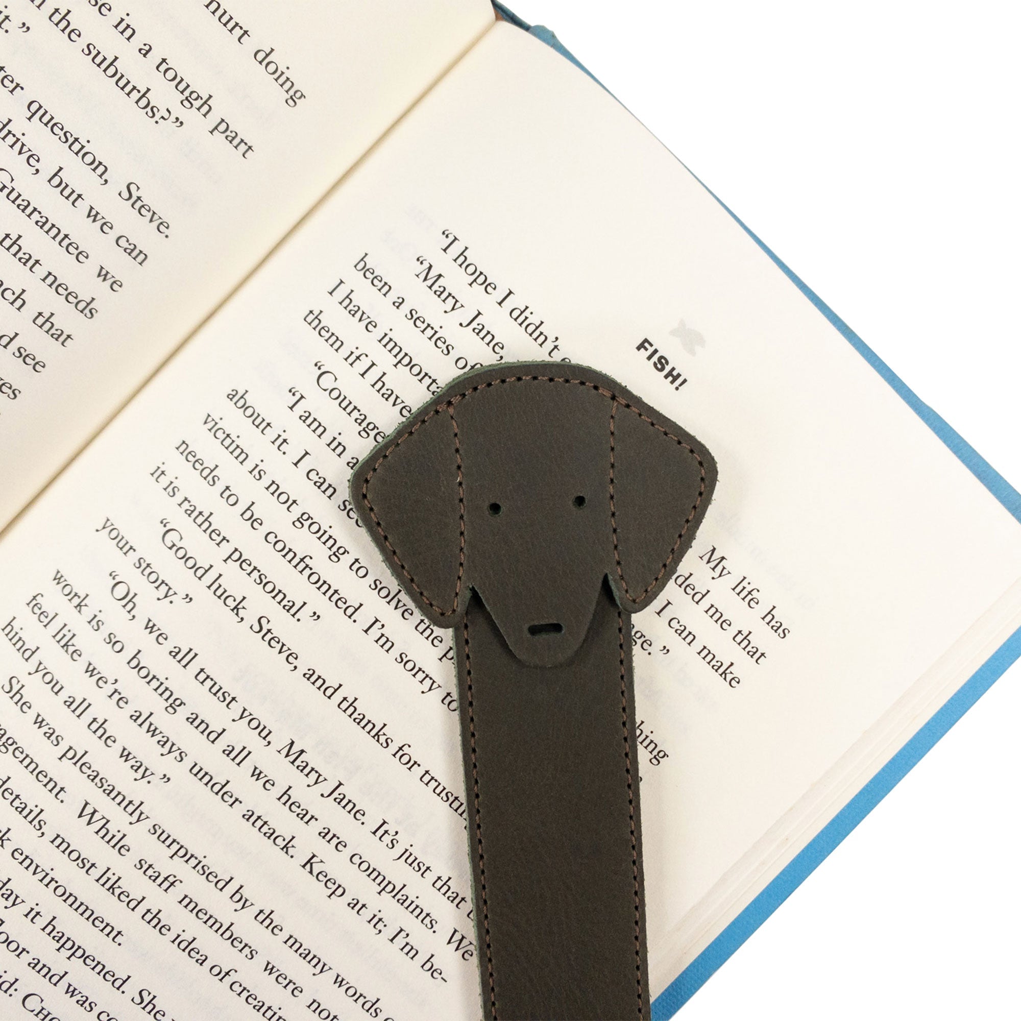 Close-up shot of Hide & Drink's brown Dog Bookmark in use, emphasizing its Full Grain Leather design. This artisanal bookmark highlights small batch production and fire branding, crafted in La Antigua Guatemala & Oaxaca Mexico.