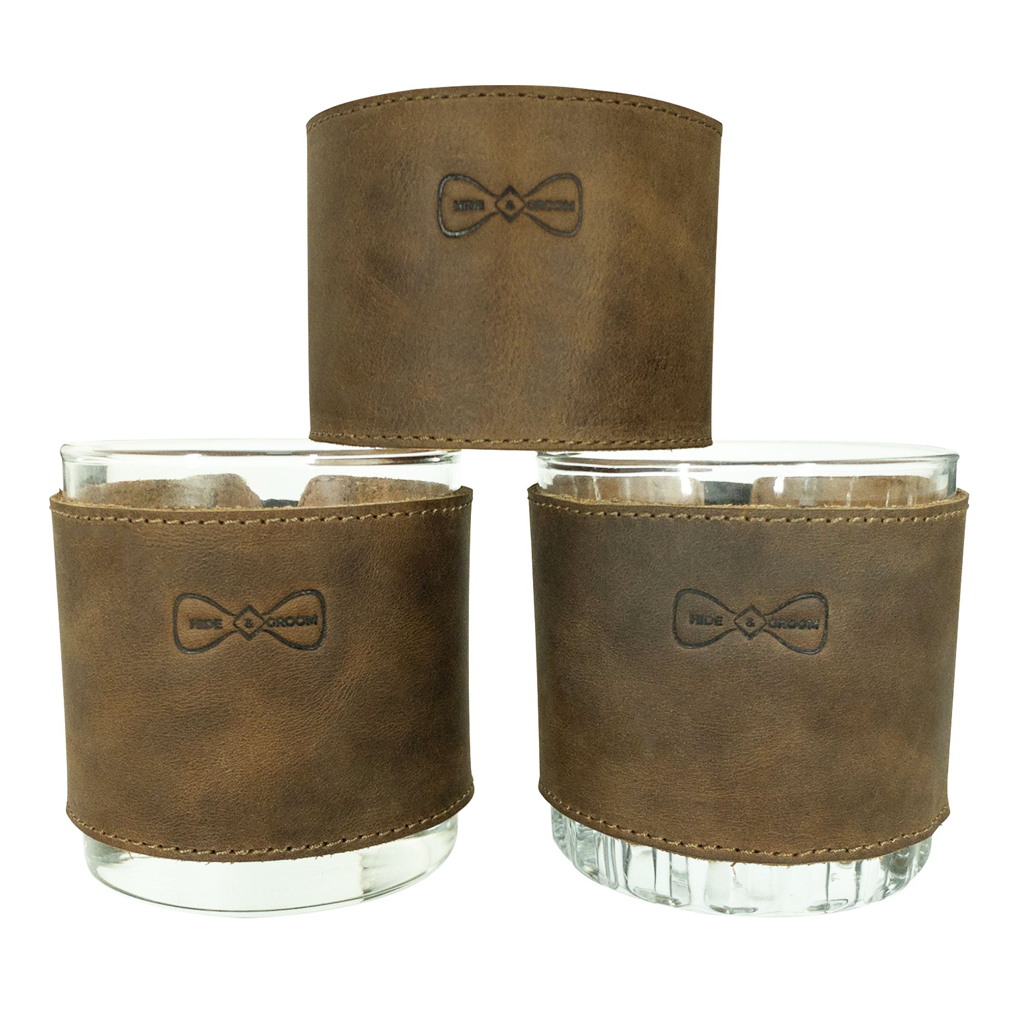 The Set of 3 Drinking Glass Covers for Groomsmen by Hide & Groom, displaying their elegant full grain leather look. Perfect for any celebration including weddings, these artisan covers are made for groomsmen, showcasing small batch production, hand cut, hand sewn craftsmanship, and a fire branded appearance, created in La Antigua Guatemala & Oaxaca Mexico.