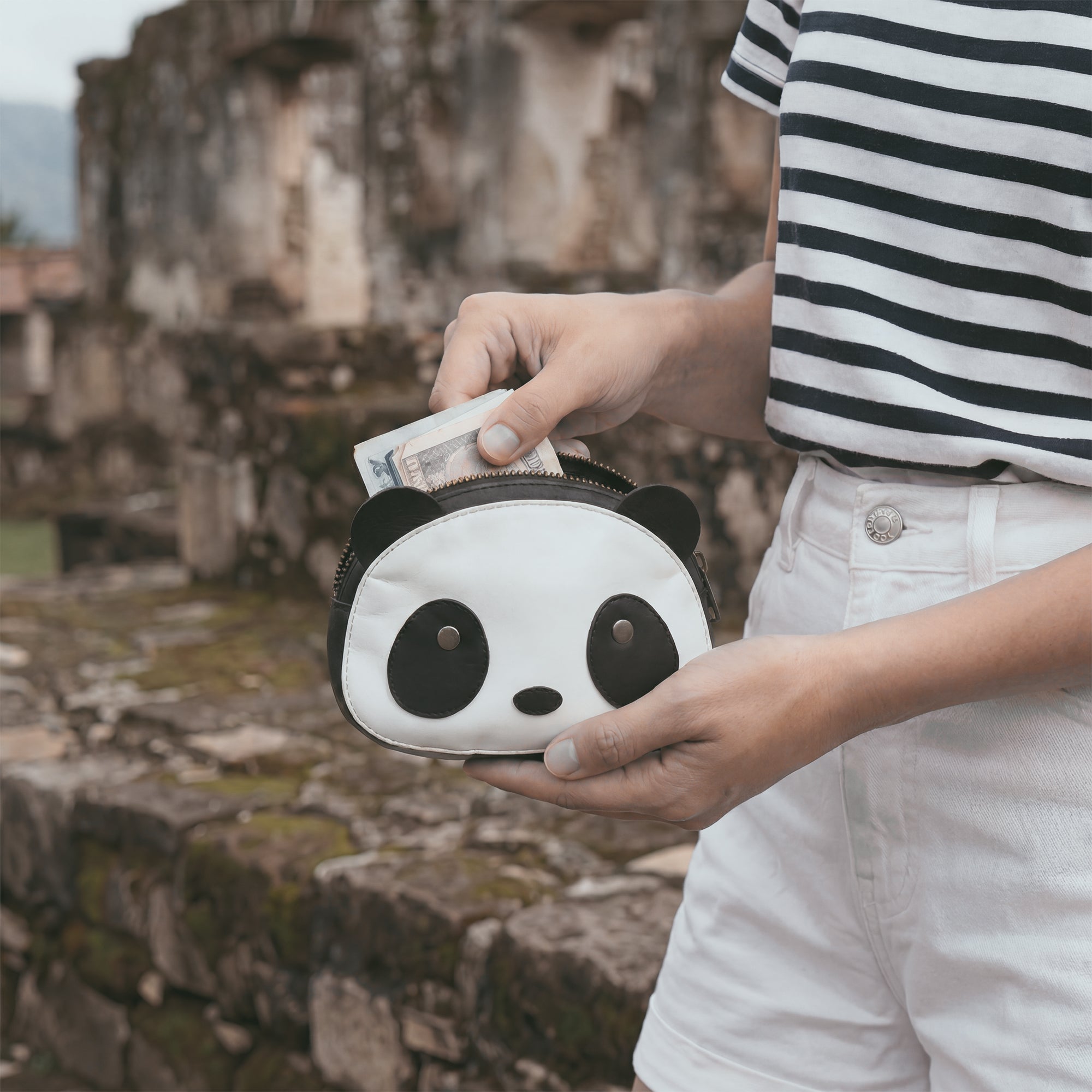 Side view of the Panda Head Shape Wallet by Hide & Drink, showing off its adorable panda features. This wallet is perfect for carrying cash, cables, cards, and travel accessories. Made from Full Grain Leather, it reflects artisan craftsmanship through small batch production, hand cut, hand sewn methods, and is fire branded, handmade in La Antigua Guatemala & Oaxaca Mexico.