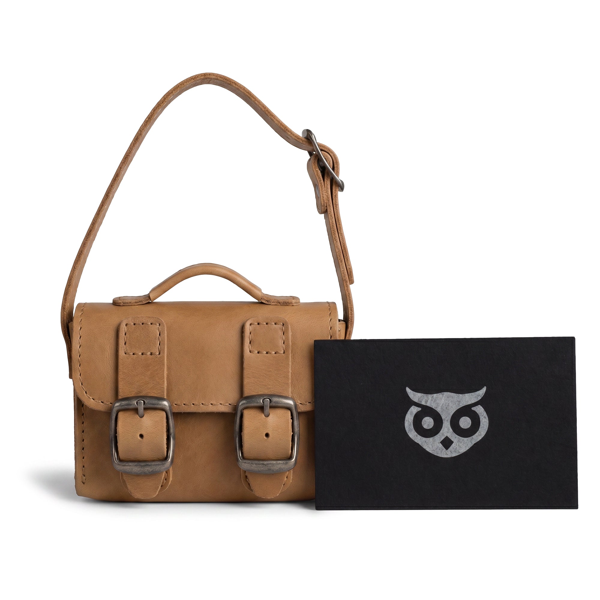 The tan Tiny Messenger Bag by Hide & Drink, presented with its tags. This artisanal Mini Messenger Bag Charm in Full Grain Leather is a useful keychain or handbag accessory, carefully made in La Antigua Guatemala.