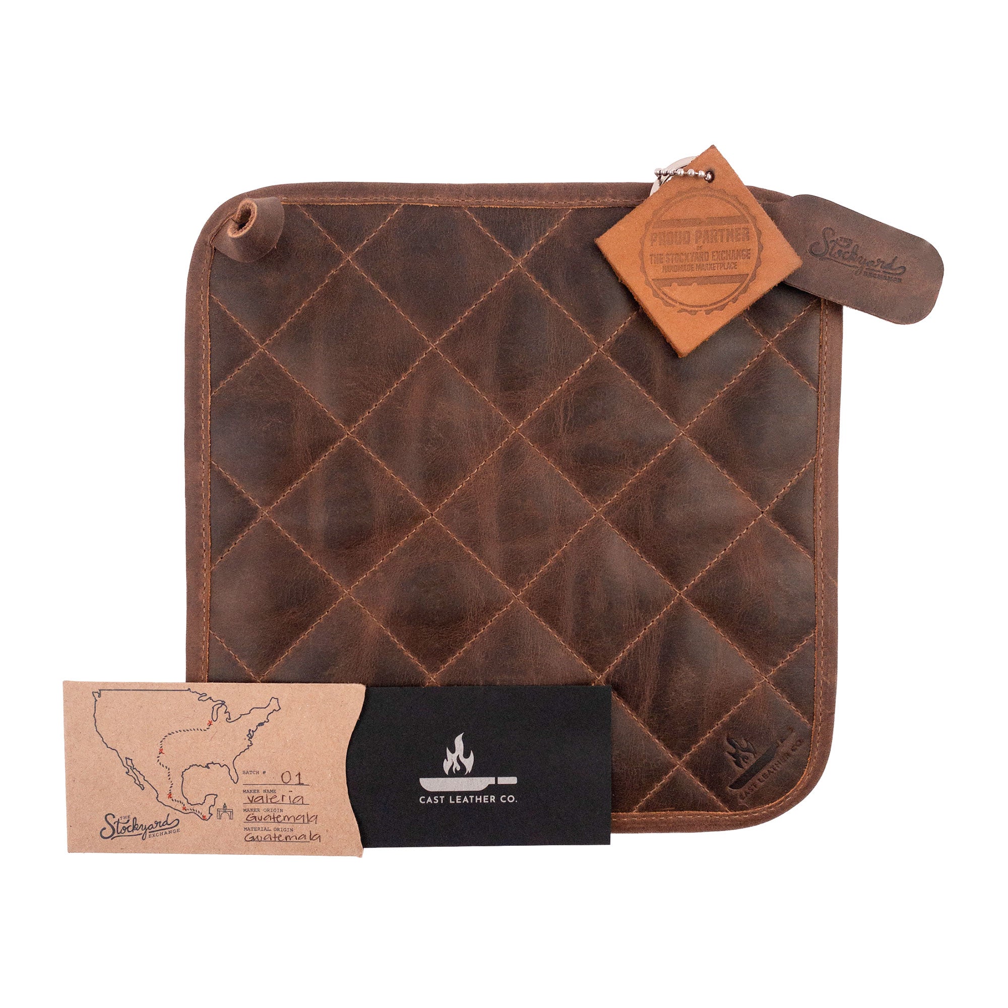 The Cast Leather Co. Squared Hot Pot Pad alongside informational tags, emphasizing its artisan-made quality. This Squared Oven Mitt Heat Resistant, Hot Pot Pad (Potholder) is great for bakery supplies and crafted from full grain leather and sheepskin. Each piece represents stockyardX's small batch production, hand cut, hand sewn, and fire branded in La Antigua Guatemala & Oaxaca Mexico.