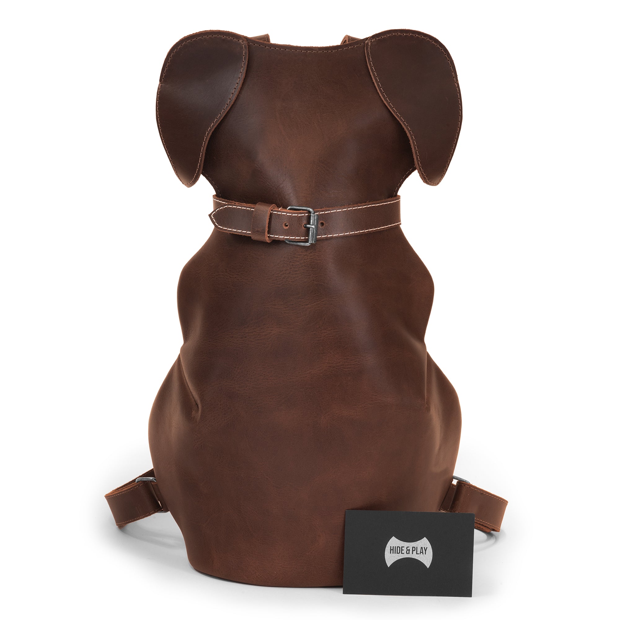 The Doggy-Shaped Backpack by Hide & Play displayed with a brand card. This Artisan bag is a unique Leather Dog-Shaped Backpack, perfect for pet lovers seeking a casual daypack with a blend of handmade artistry and everyday functionality in full grain leather.