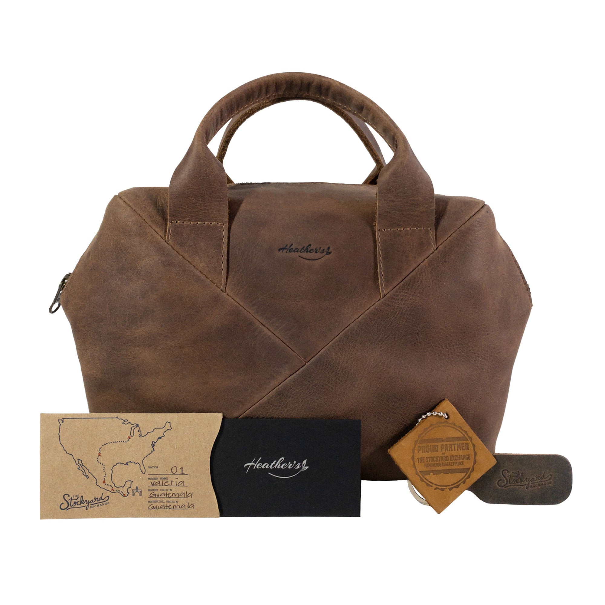 Heather's Fluffy Purse with accessories and tags, emphasizing its Full Grain Leather quality. As a Leather Fluffy Purse, it serves as a chic Handbag for Women, trendy Night Bag, and functional Rectangular Purse with Zipper. This bag is crafted in Small Batch Production focusing on Hand Cut and Hand Sewn techniques, Fire Branded, and is proudly Handmade in La Antigua Guatemala & Oaxaca Mexico.