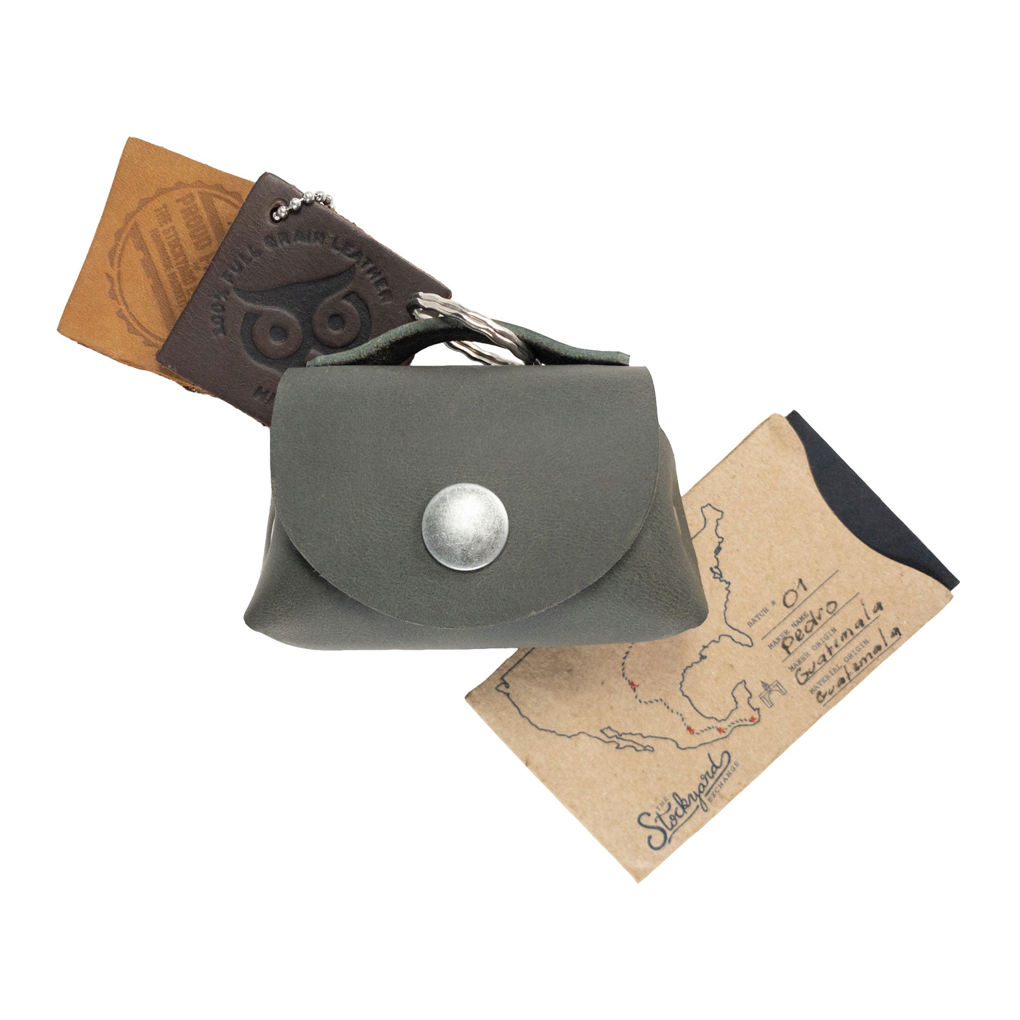 Top view of the Tiny Handbag Keychain by Hide & Drink, displaying the Tiny Handbag with Key Ring Holder along with its unique packaging. This product, crafted from Full Grain Leather, reflects Small Batch Production, is Hand Cut, Hand Sewn, and Fire Branded, highlighting its Handmade quality from La Antigua Guatemala & Oaxaca Mexico.