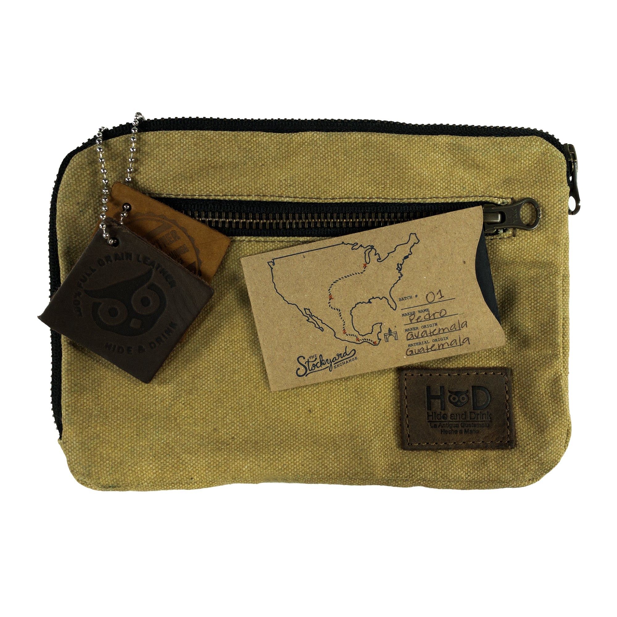 Hide & Drink's Zipper Gear Pouch with artisan tags and map, emphasizing its handmade quality and the craftsmanship involved in its creation, made from water resistant waxed canvas.